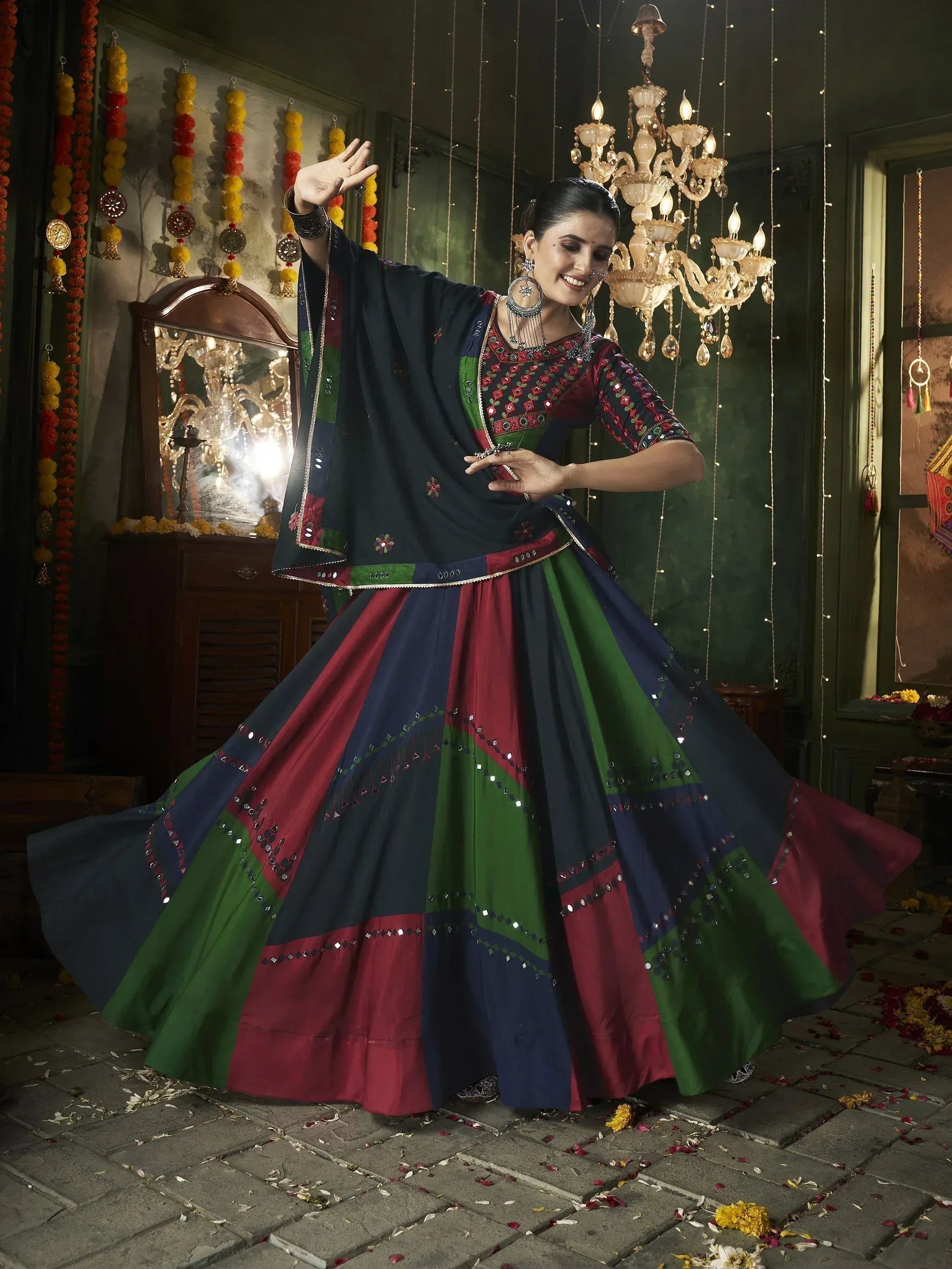 Woman in colorful Indian ethnic lehenga choli with mirror work, dancing under chandelier