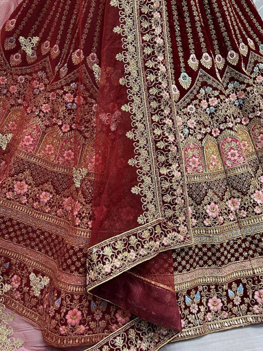 Maroon velvet lehenga with gold and pink floral embroidery, perfect for Indian weddings and festive occasions.