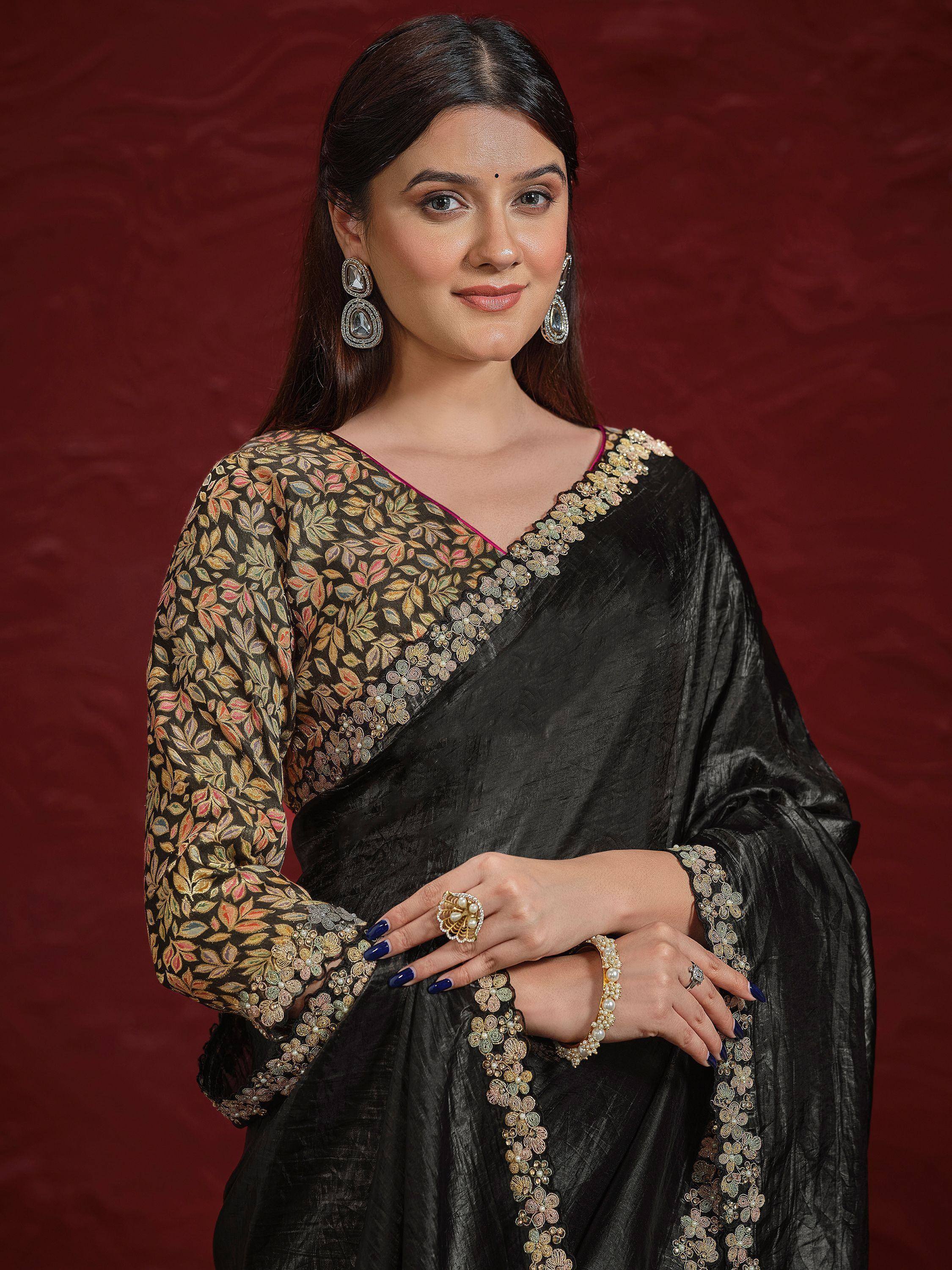 Black saree with floral embroidery and gold detailing, paired with statement earrings and pearl jewelry
