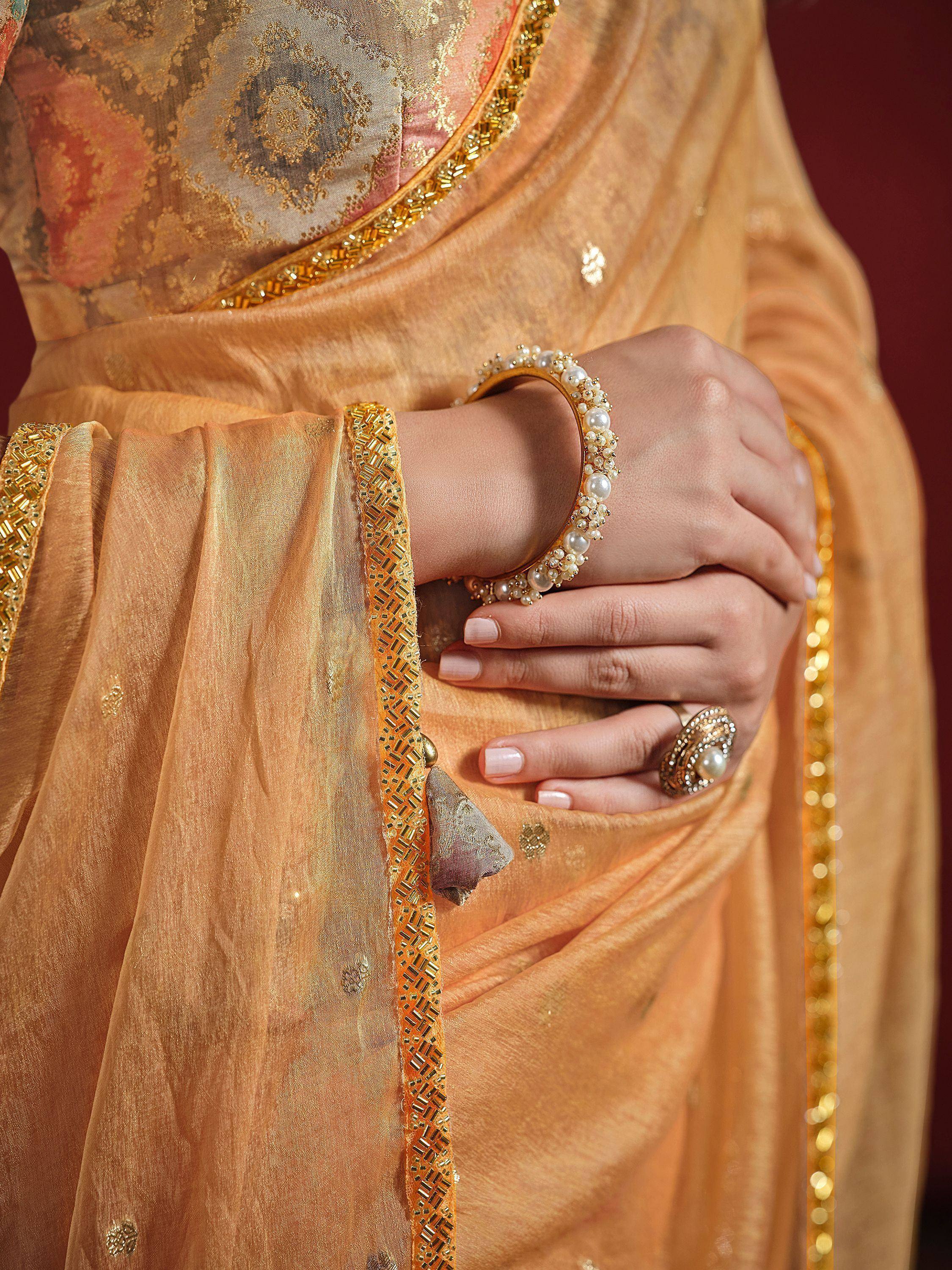 Elegant golden saree with intricate embroidery and pearl jewelry, perfect for Indian ethnic wear occasions.