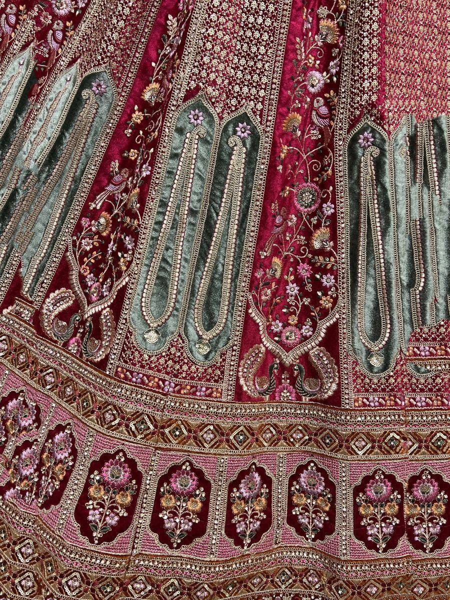 Richly embroidered maroon and green lehenga with floral and paisley motifs, perfect for Indian ethnic wear.