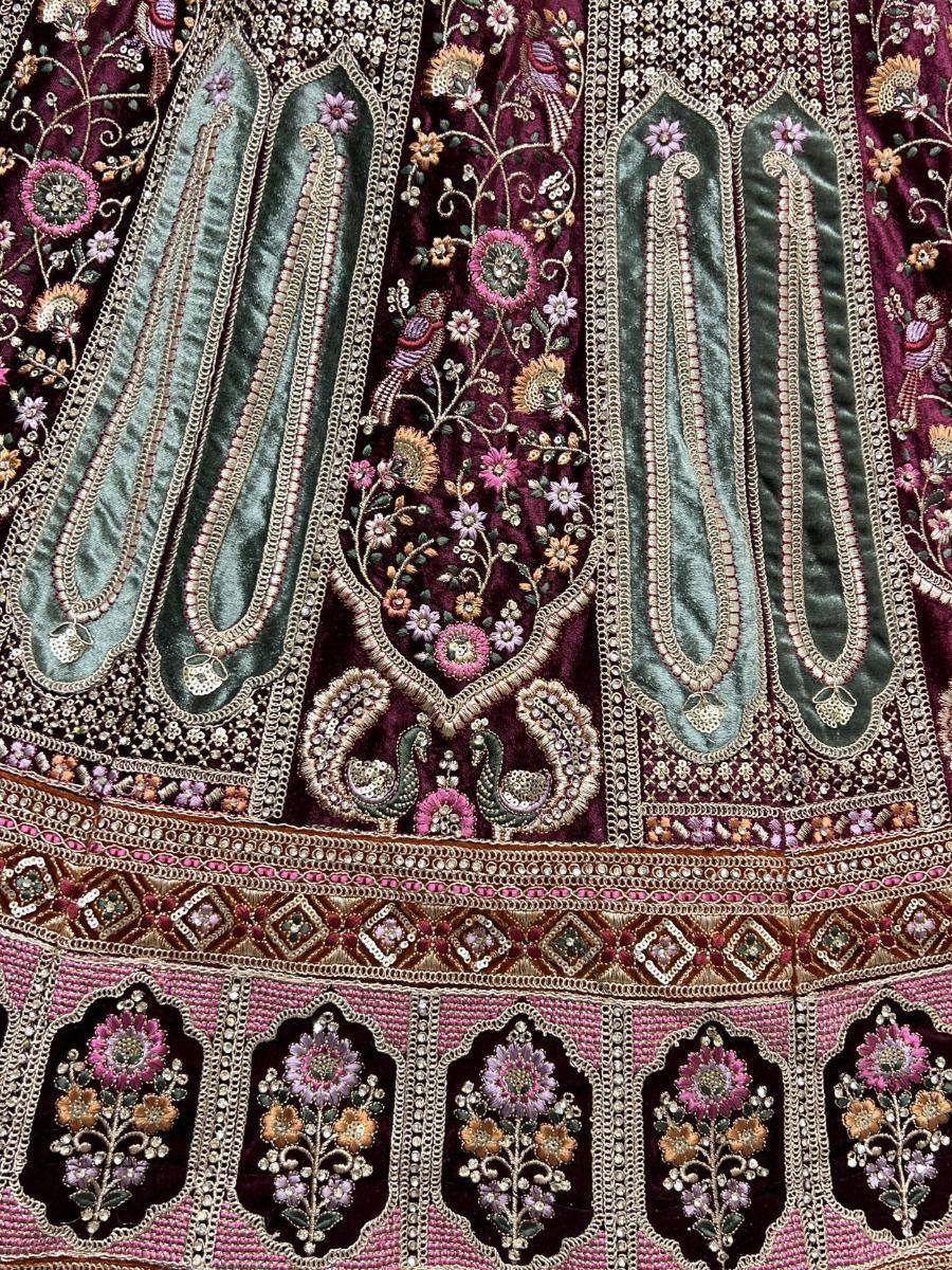 Richly embroidered maroon and green lehenga with floral and paisley motifs, perfect for Indian ethnic wear.