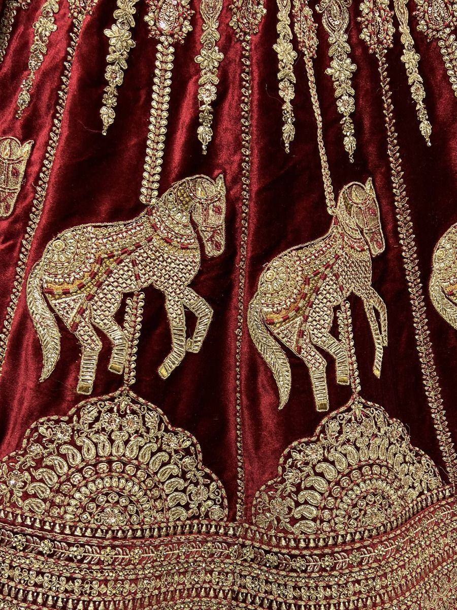 Rich maroon velvet lehenga with gold horse embroidery and intricate zari work, perfect for Indian ethnic wear.