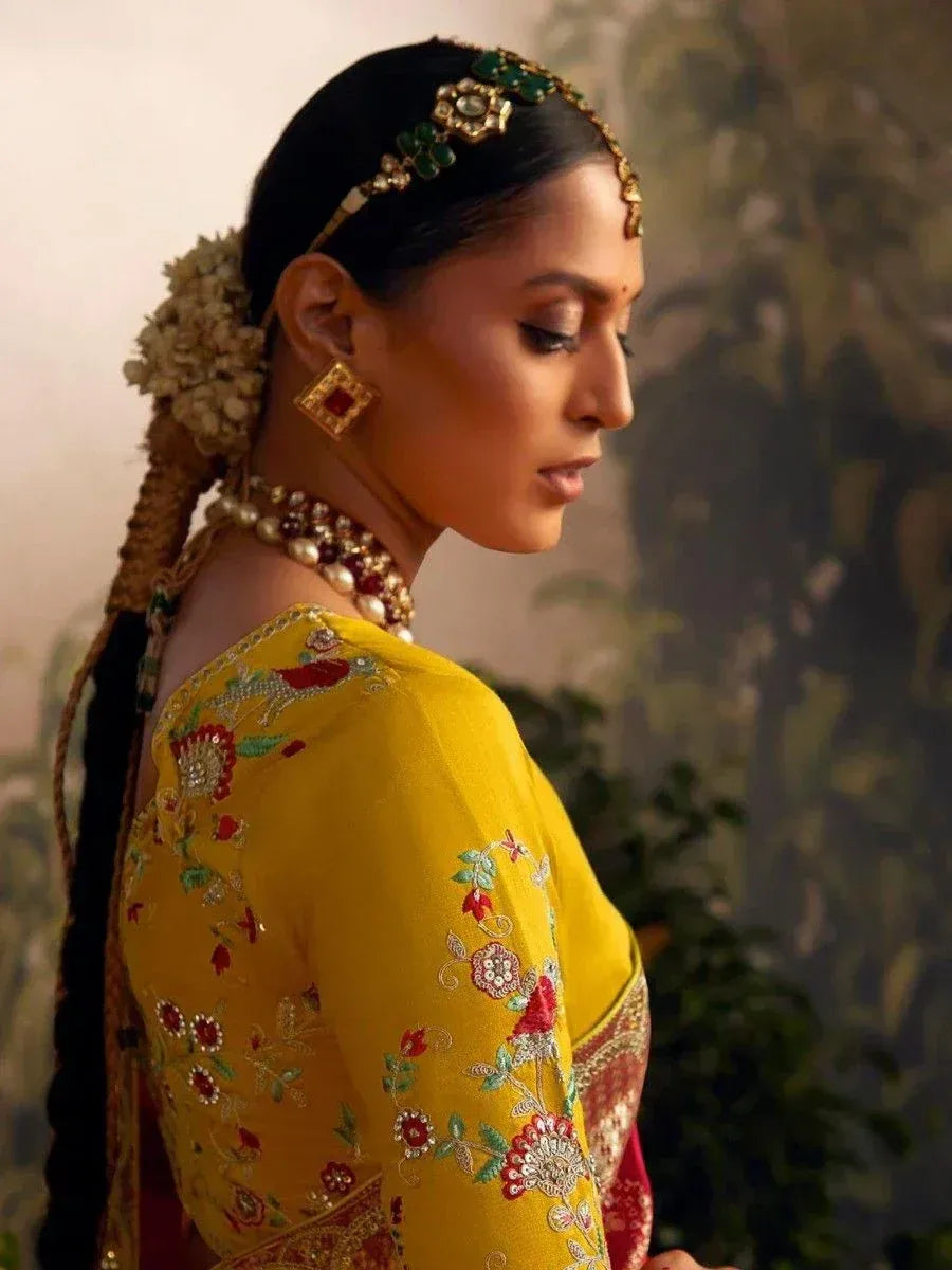 Woman in yellow embroidered lehenga choli with floral motifs, traditional jewelry, and gajra hairstyle