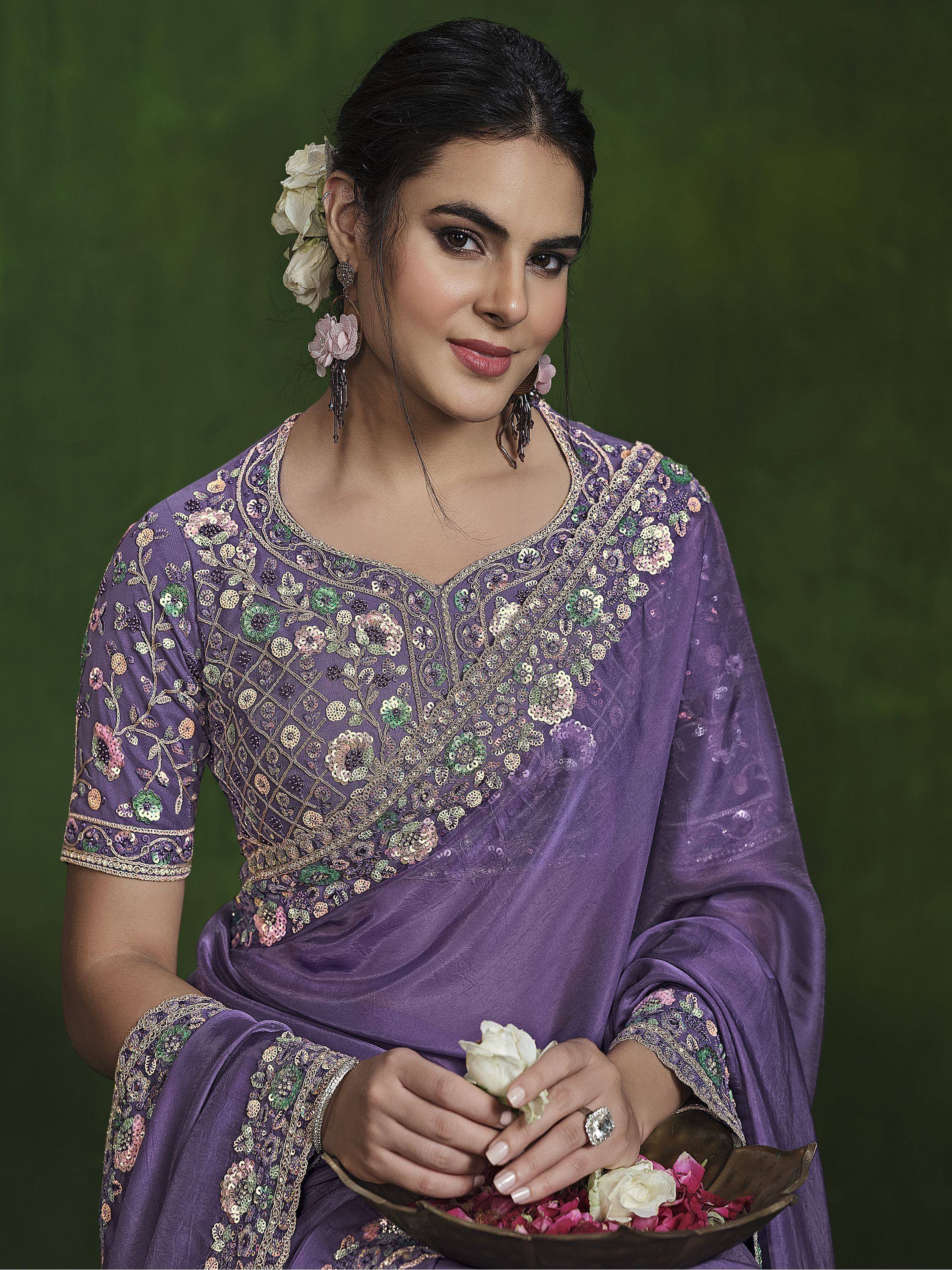Woman in purple embroidered Indian saree with floral sequin work, holding rose petals