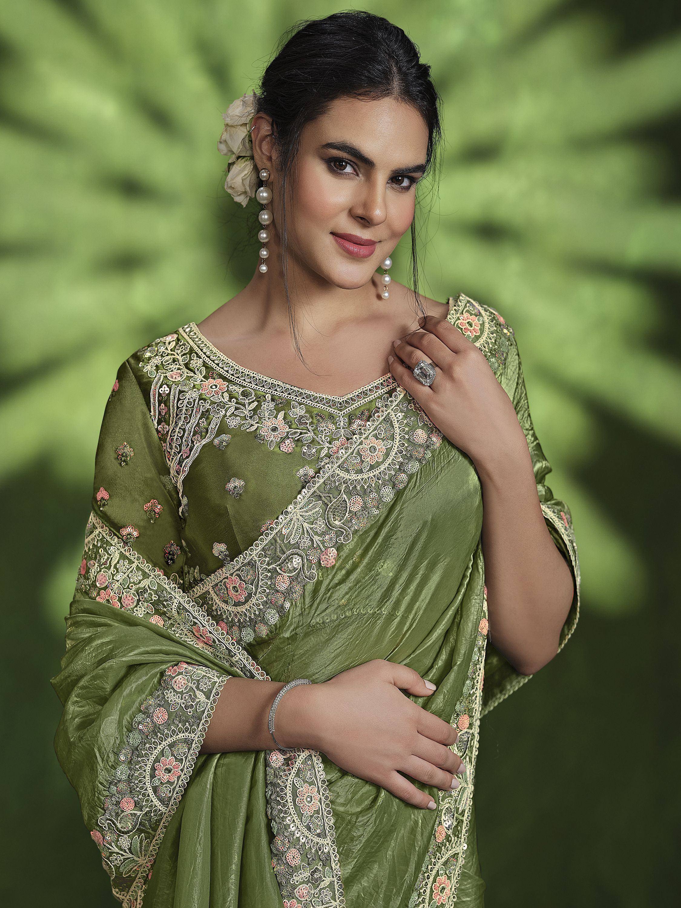Woman in olive green embroidered saree with floral details, pearl earrings, and ring, styled for ethnic occasions