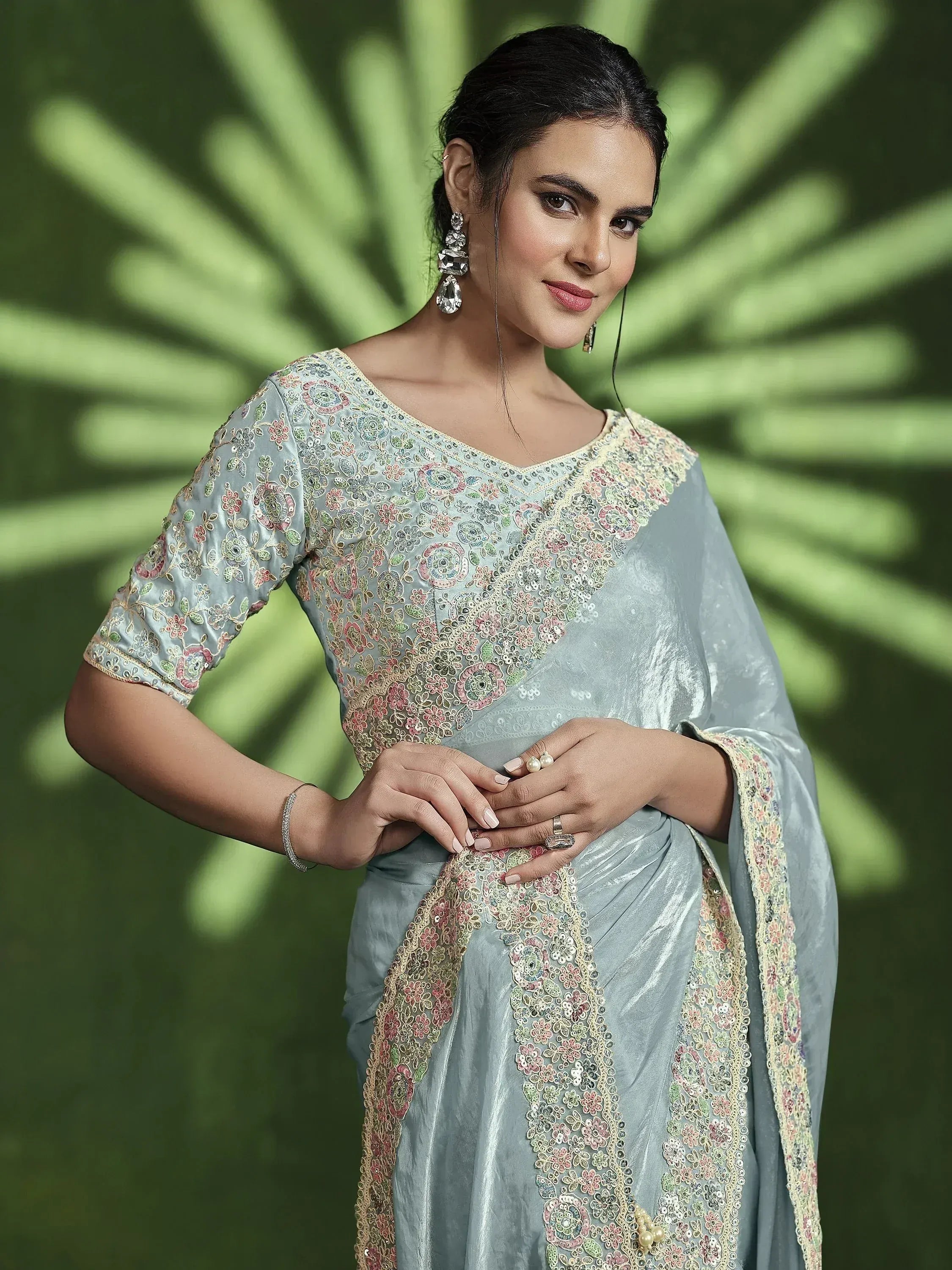 Elegant woman in light blue embroidered saree with floral detailing, styled for ethnic occasions.