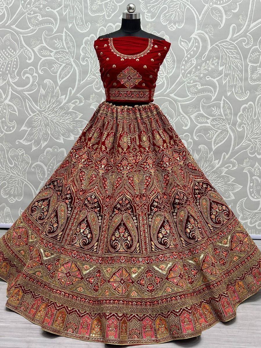Red velvet designer lehenga choli with intricate gold embroidery and paisley motifs, perfect for Indian weddings and festive occasions.