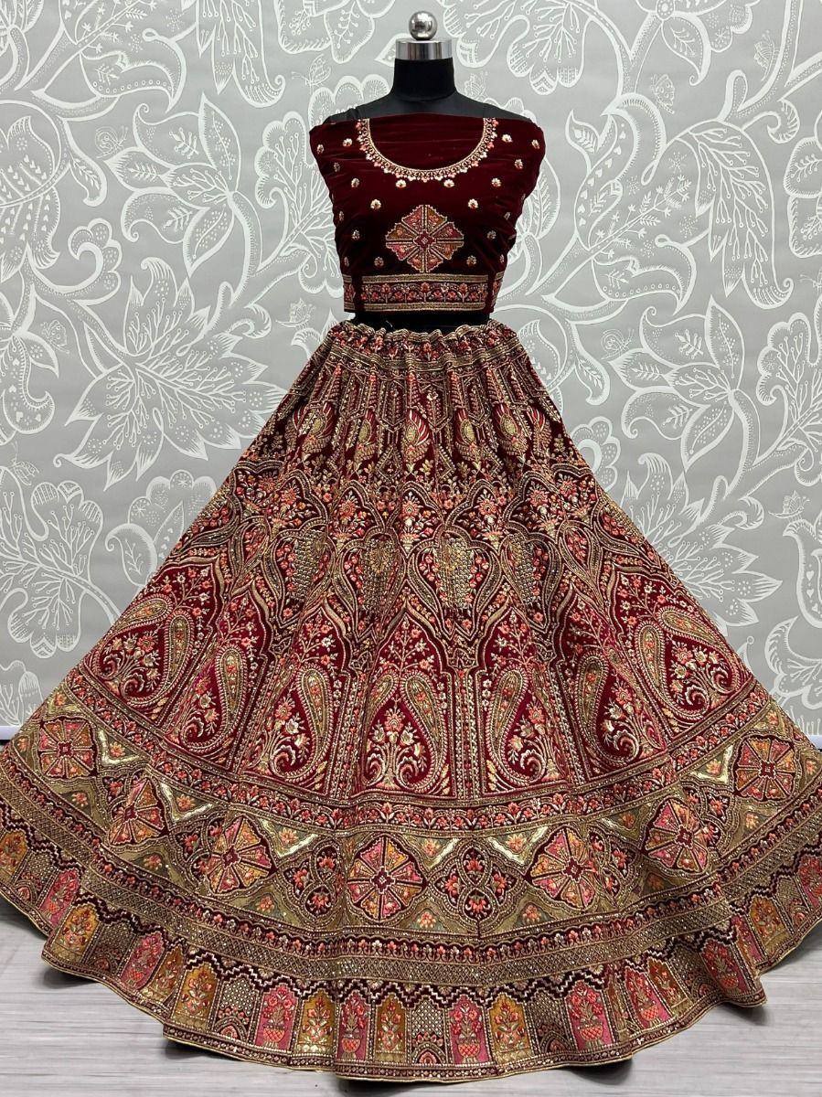 Maroon velvet designer lehenga choli with intricate gold embroidery and paisley patterns, perfect for weddings