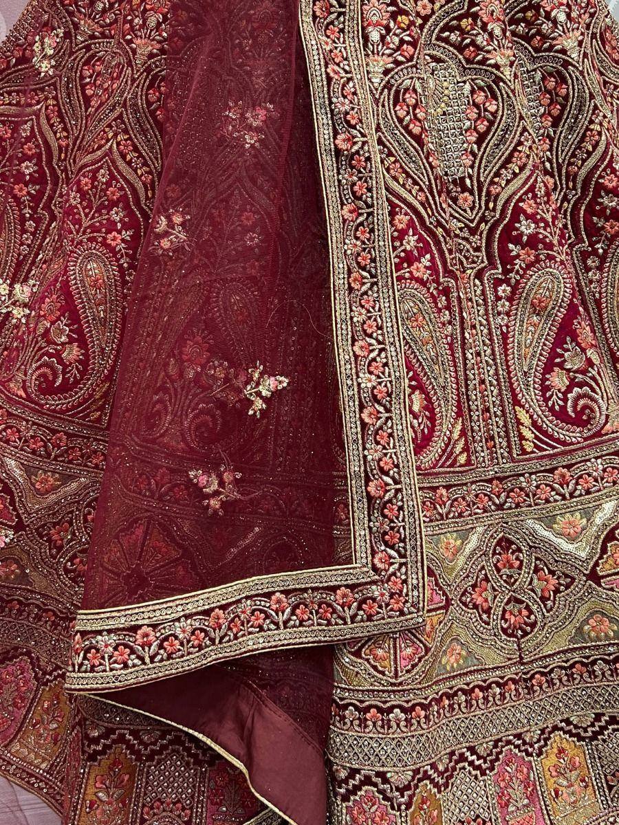 Luxury maroon ethnic wear with intricate gold embroidery and floral patterns, perfect for festive occasions.