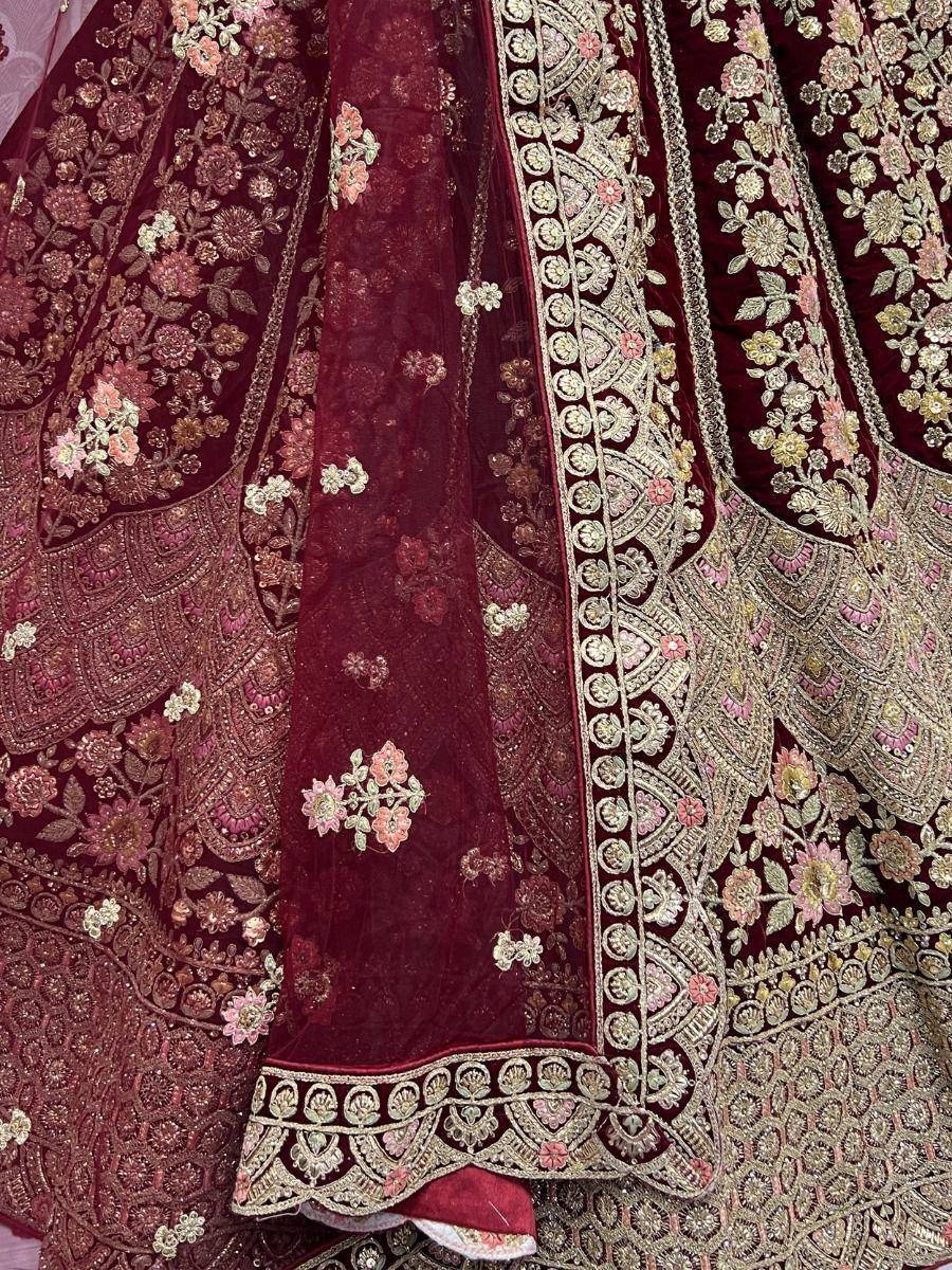 Luxury maroon velvet lehenga with intricate gold and pink floral embroidery, perfect for Indian weddings.