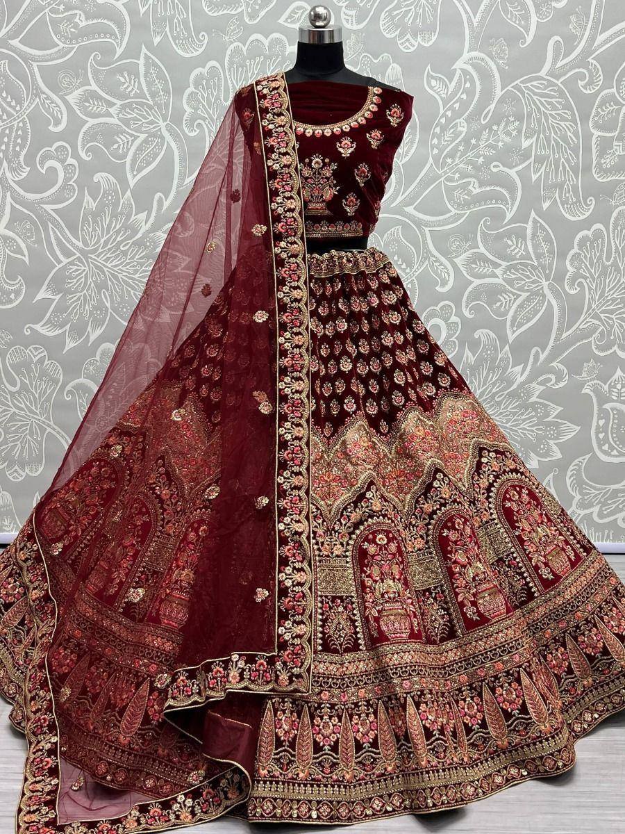 Maroon velvet lehenga choli with heavy gold embroidery and floral dupatta, ideal for Indian weddings and festive occasions.