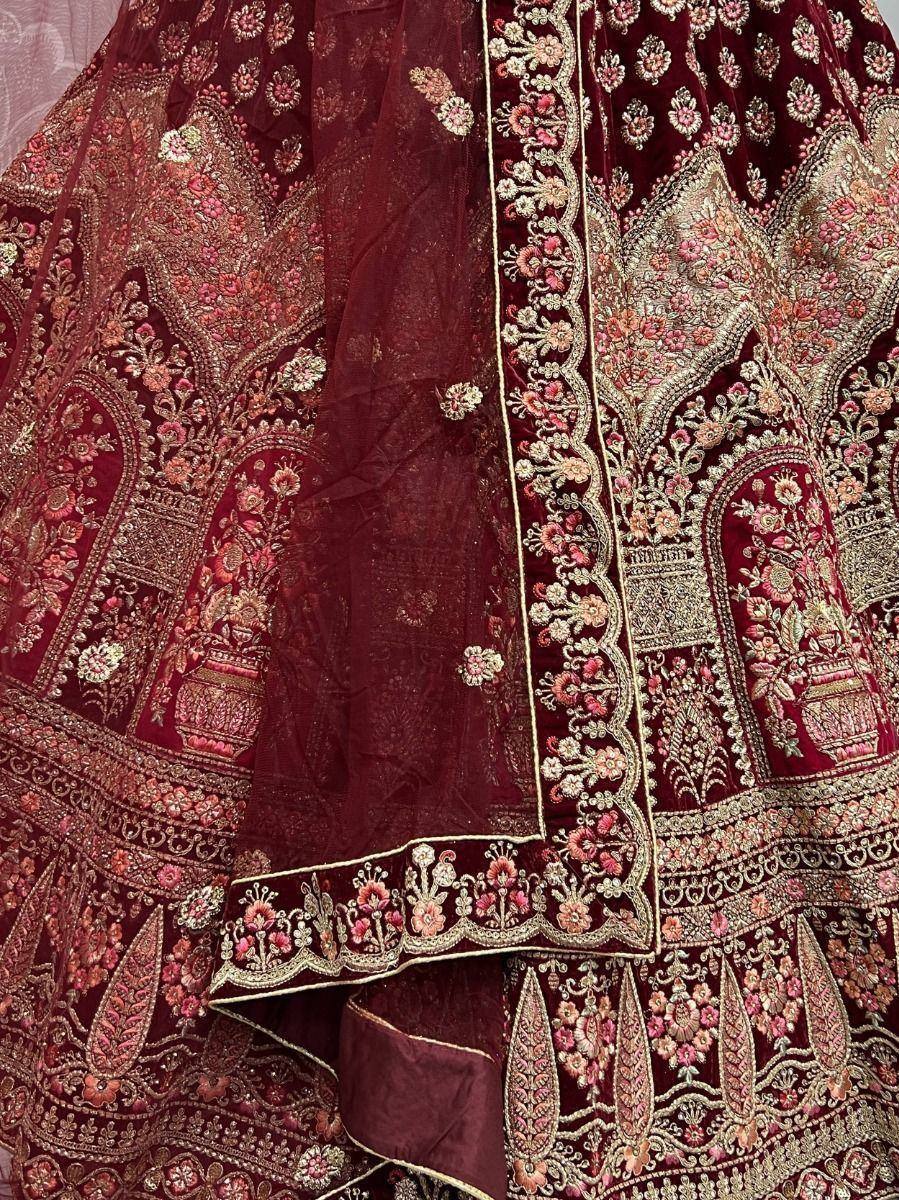 Maroon velvet lehenga choli with intricate gold and pink floral embroidery, perfect for Indian weddings.