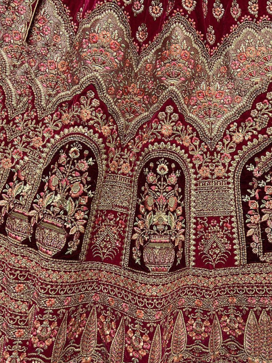 Rich maroon velvet lehenga with intricate gold floral embroidery and vase motifs, perfect for Indian ethnic wear.