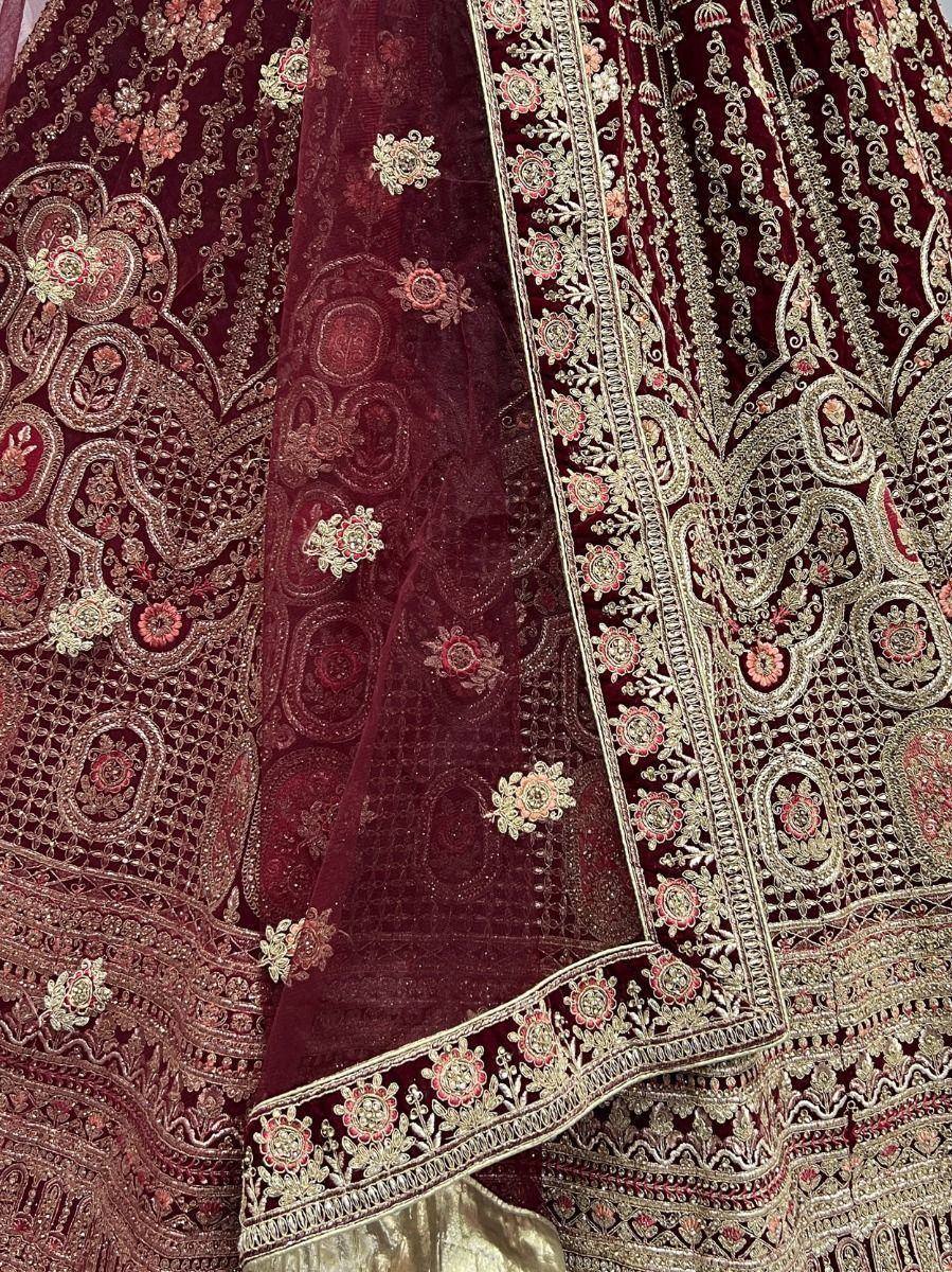 Rich maroon velvet lehenga choli with intricate gold and pink embroidery, perfect for Indian weddings and festive occasions.