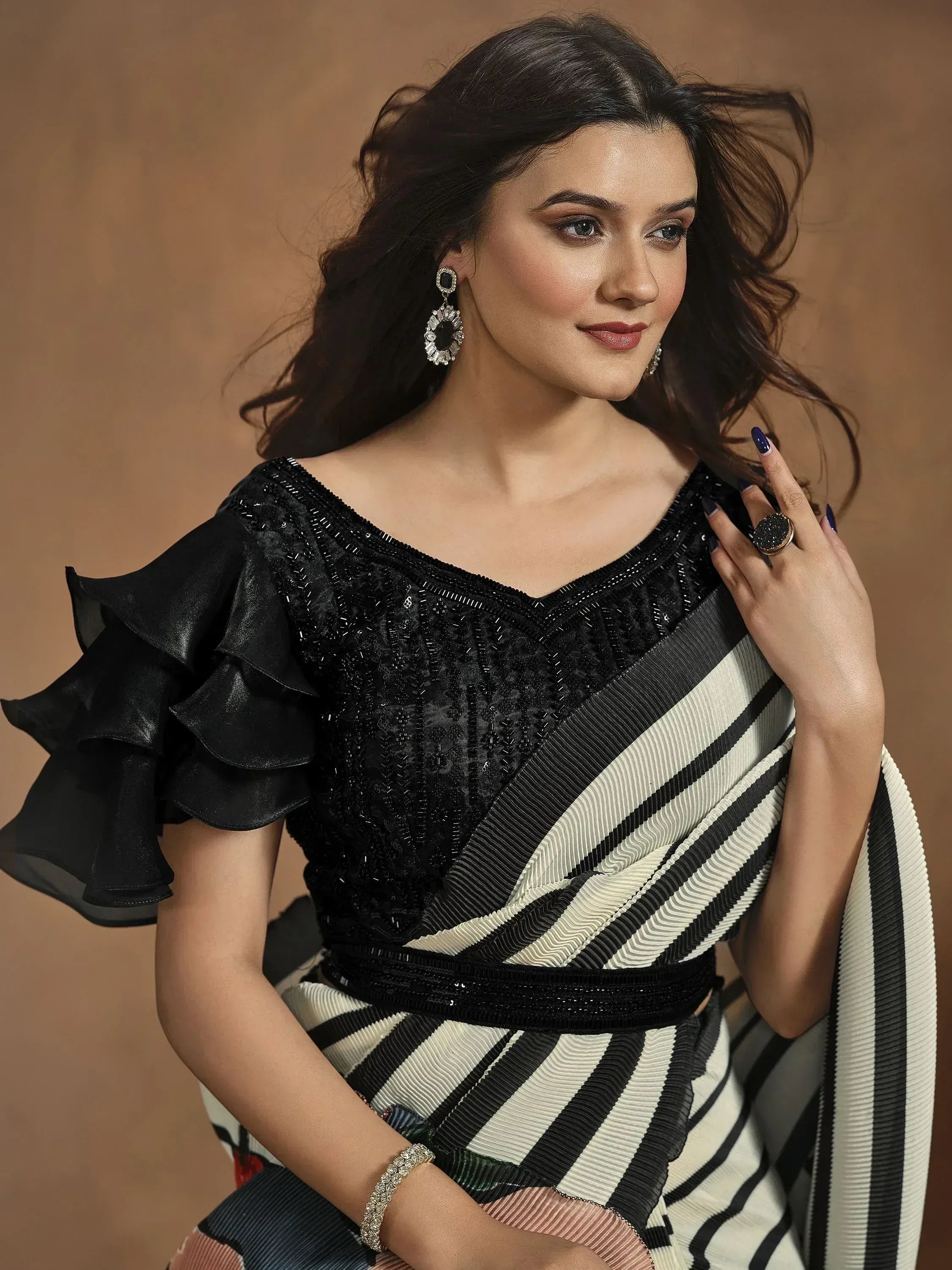 Woman in black sequin blouse with ruffle sleeves and striped saree, elegant ethnic wear