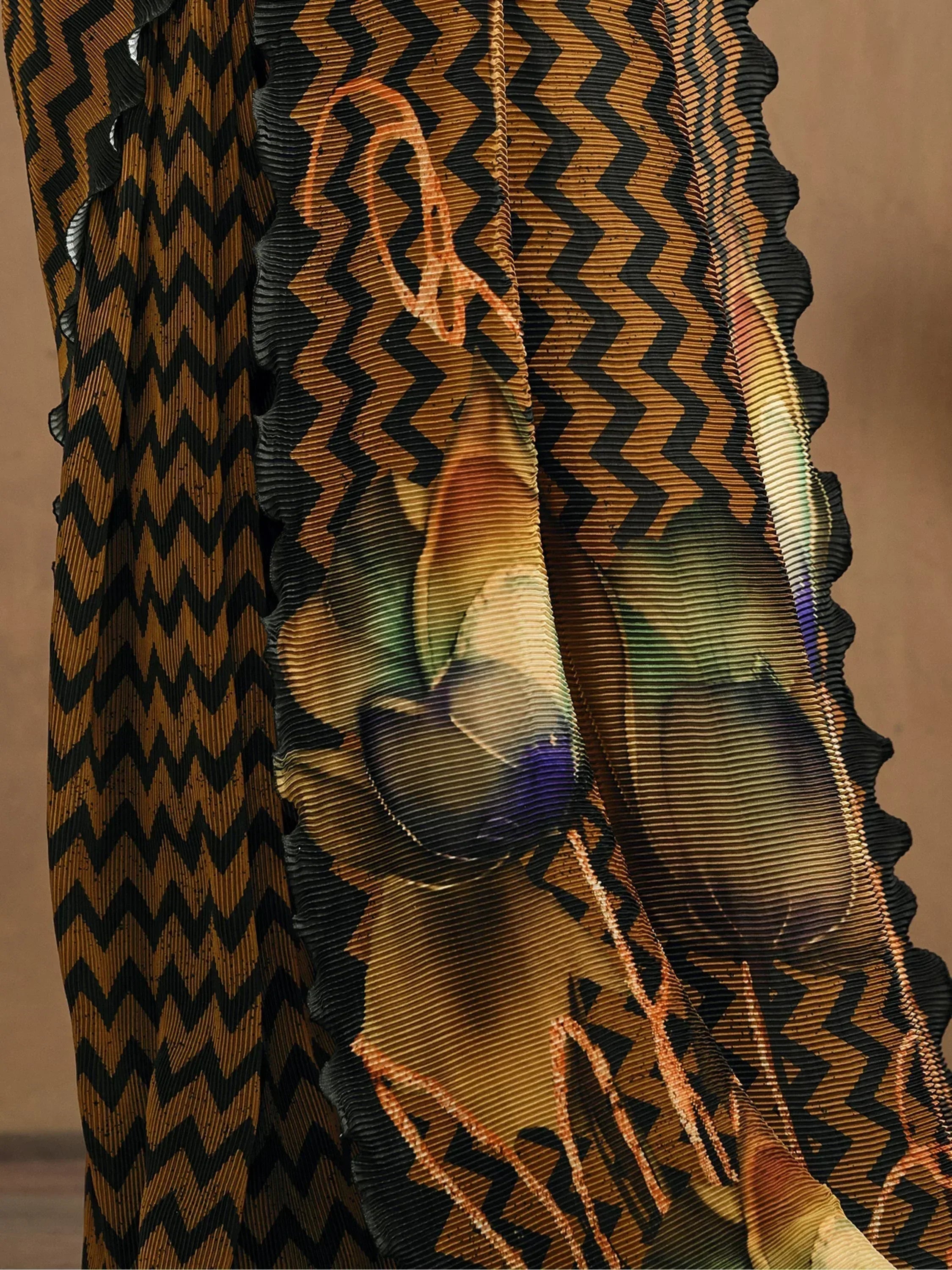 Ethnic gown with bold chevron print and ruffled hem, featuring vibrant abstract floral design on pleated fabric.