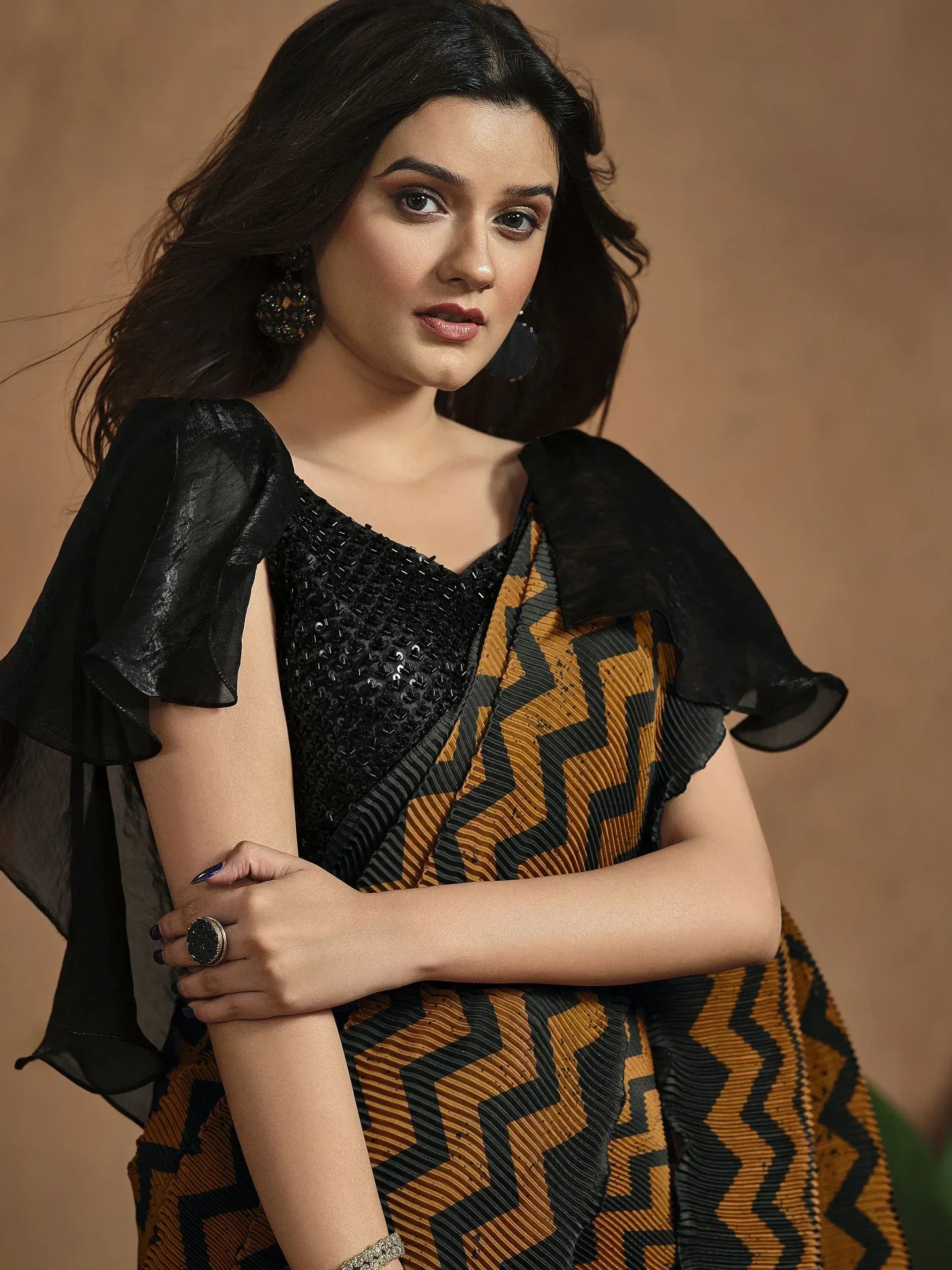 Woman in black sequin top with sheer cape, mustard and black geometric saree, ethnic Indian wear