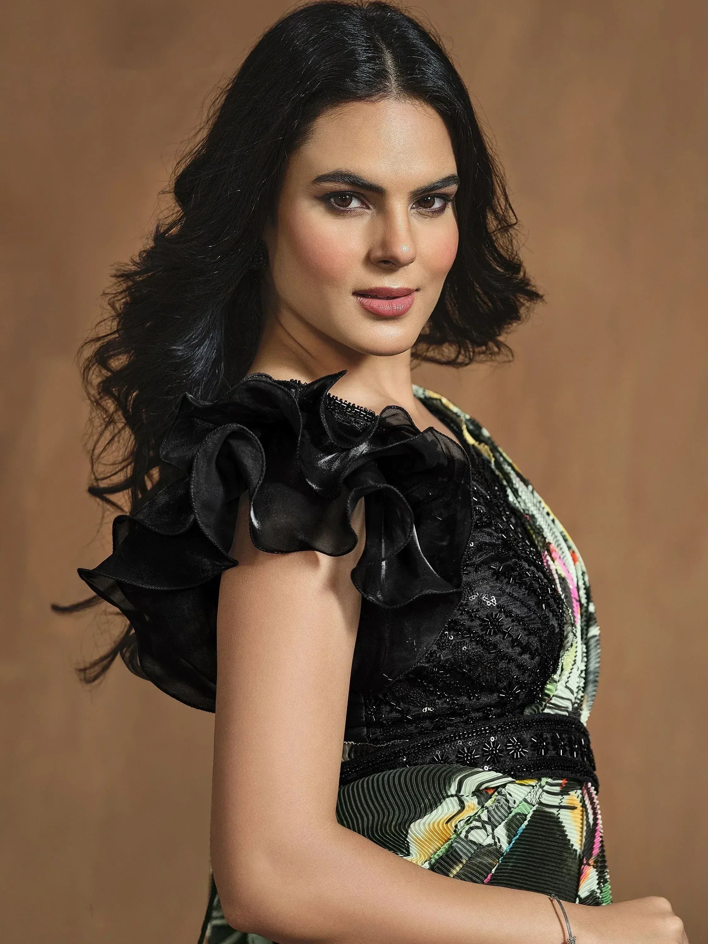 Woman in black ruffle top with sequin embellishments and colorful printed skirt, ethnic wear style