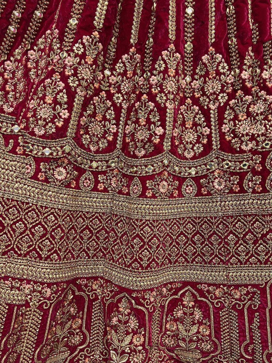 Rich maroon velvet lehenga with gold floral embroidery and mirror work, perfect for Indian weddings