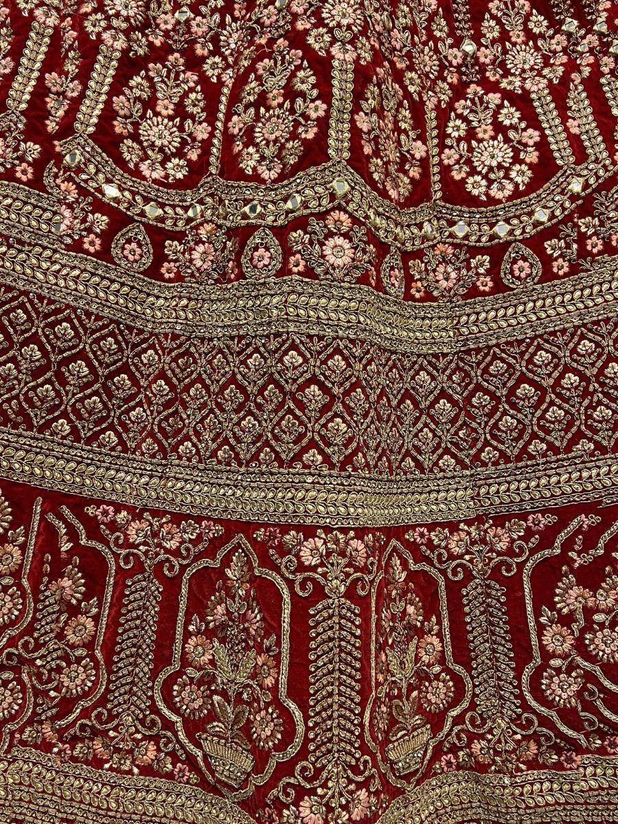 Rich maroon velvet lehenga with intricate gold and pink floral embroidery, perfect for Indian ethnic wear.