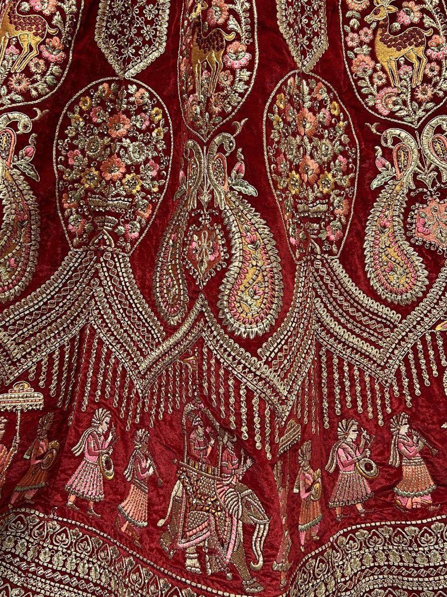 Richly embroidered maroon velvet lehenga with floral, deer, and royal court motifs, perfect for Indian ethnic wear.