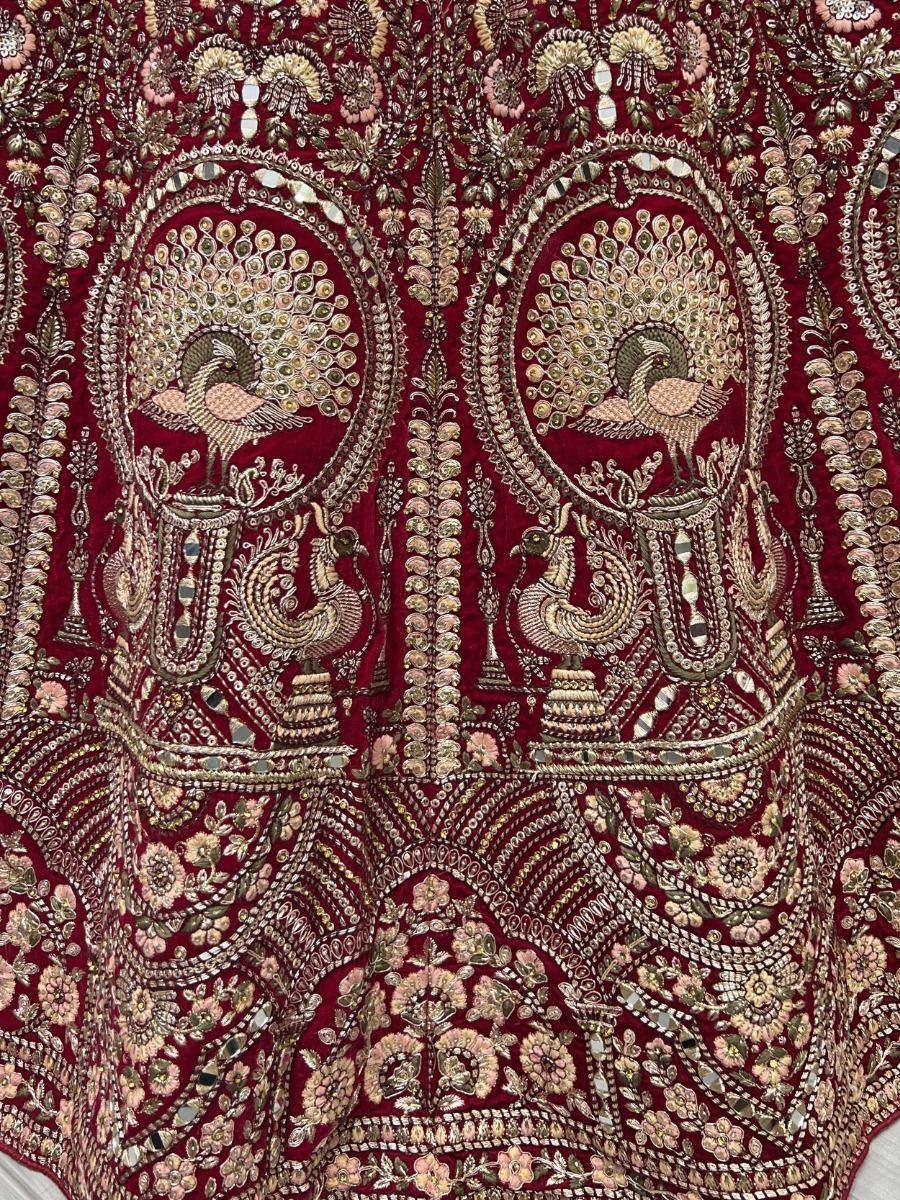 Rich maroon ethnic gown with peacock embroidery and mirror work, perfect for Indian weddings and festive occasions.