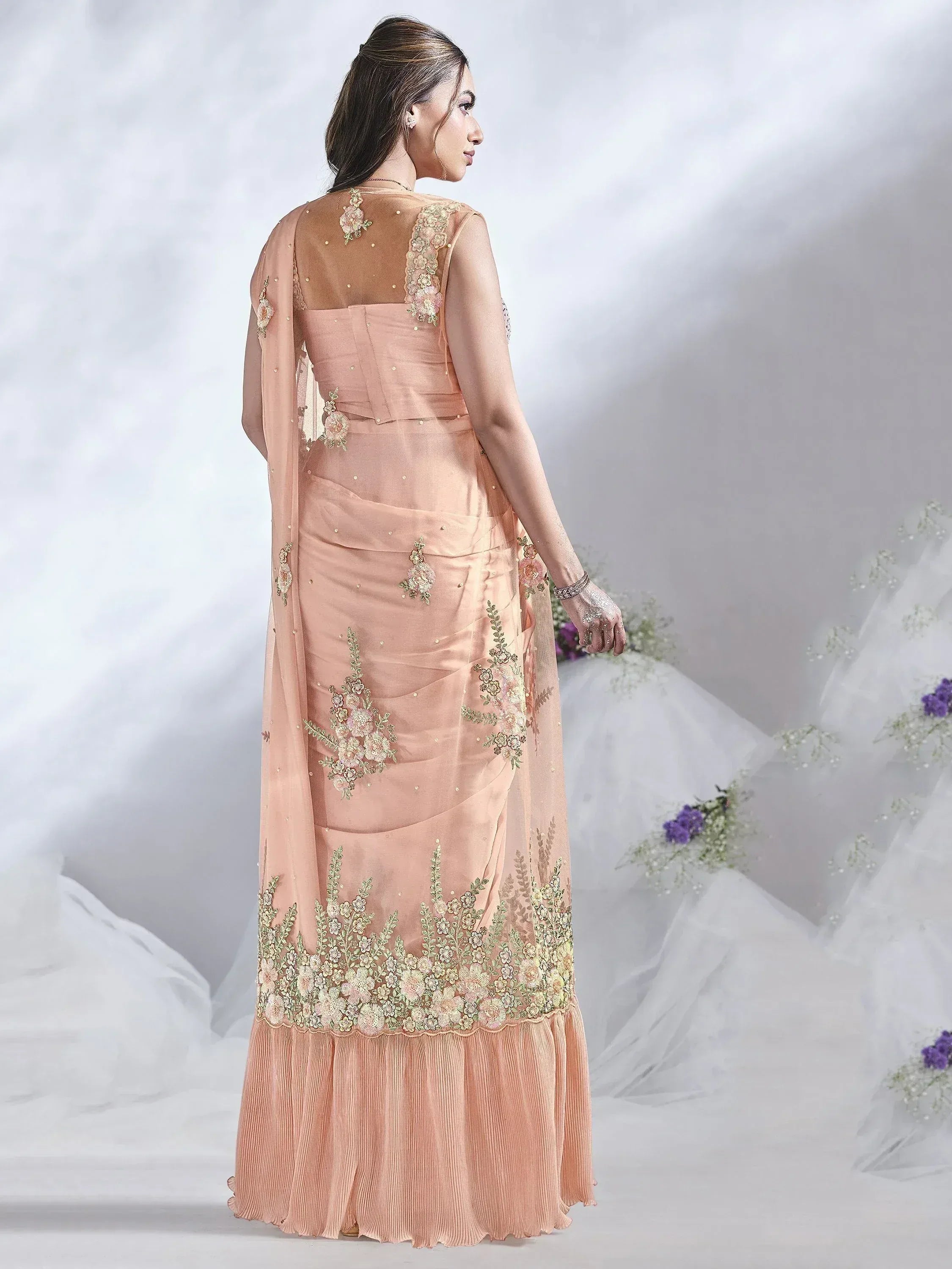 Peach floral embroidered ethnic gown with sheer overlay and pleated hem, perfect for Indian occasions.