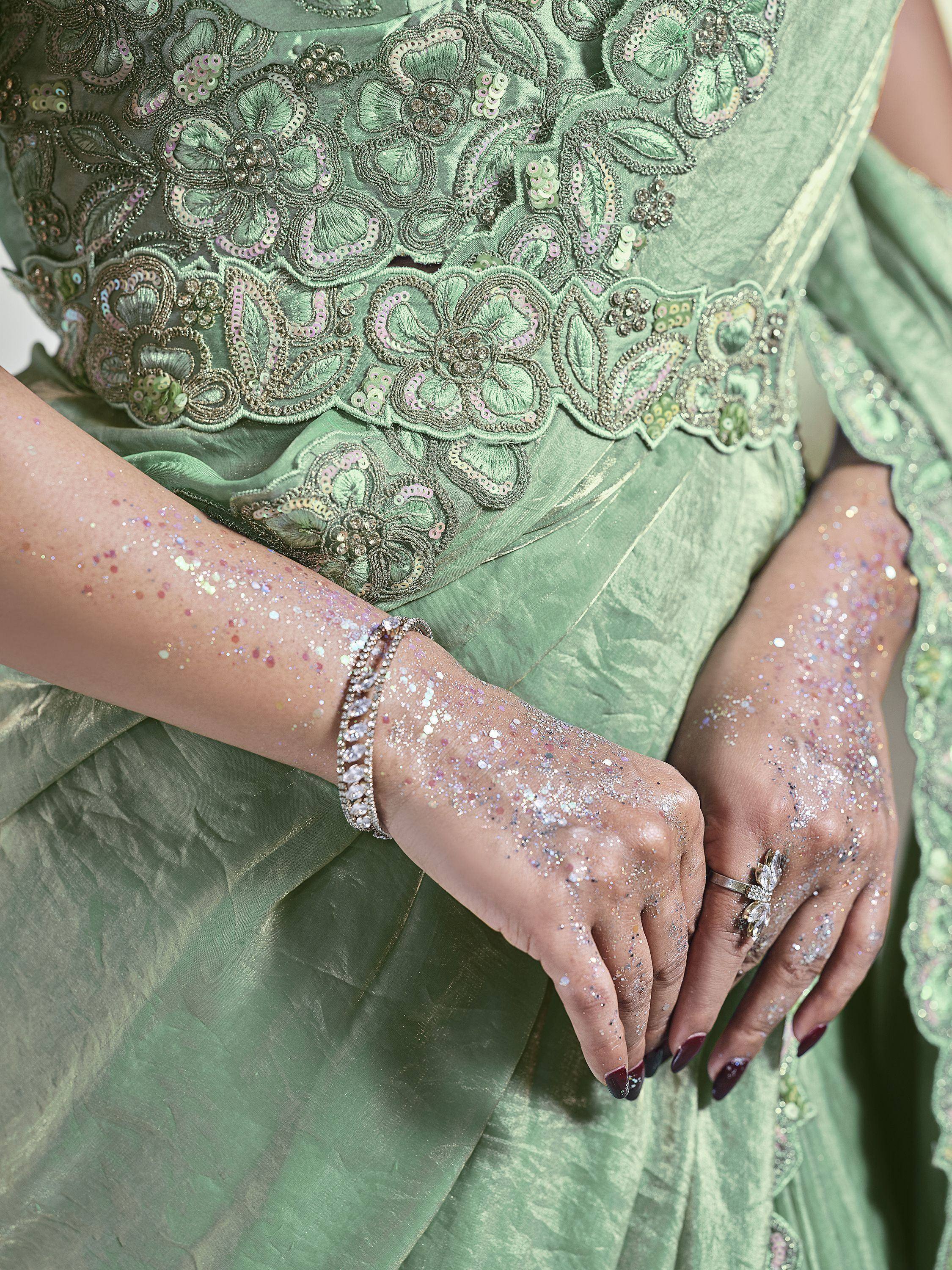 Mint green embroidered ethnic gown with sequin detailing, glitter on hands, and statement jewelry.