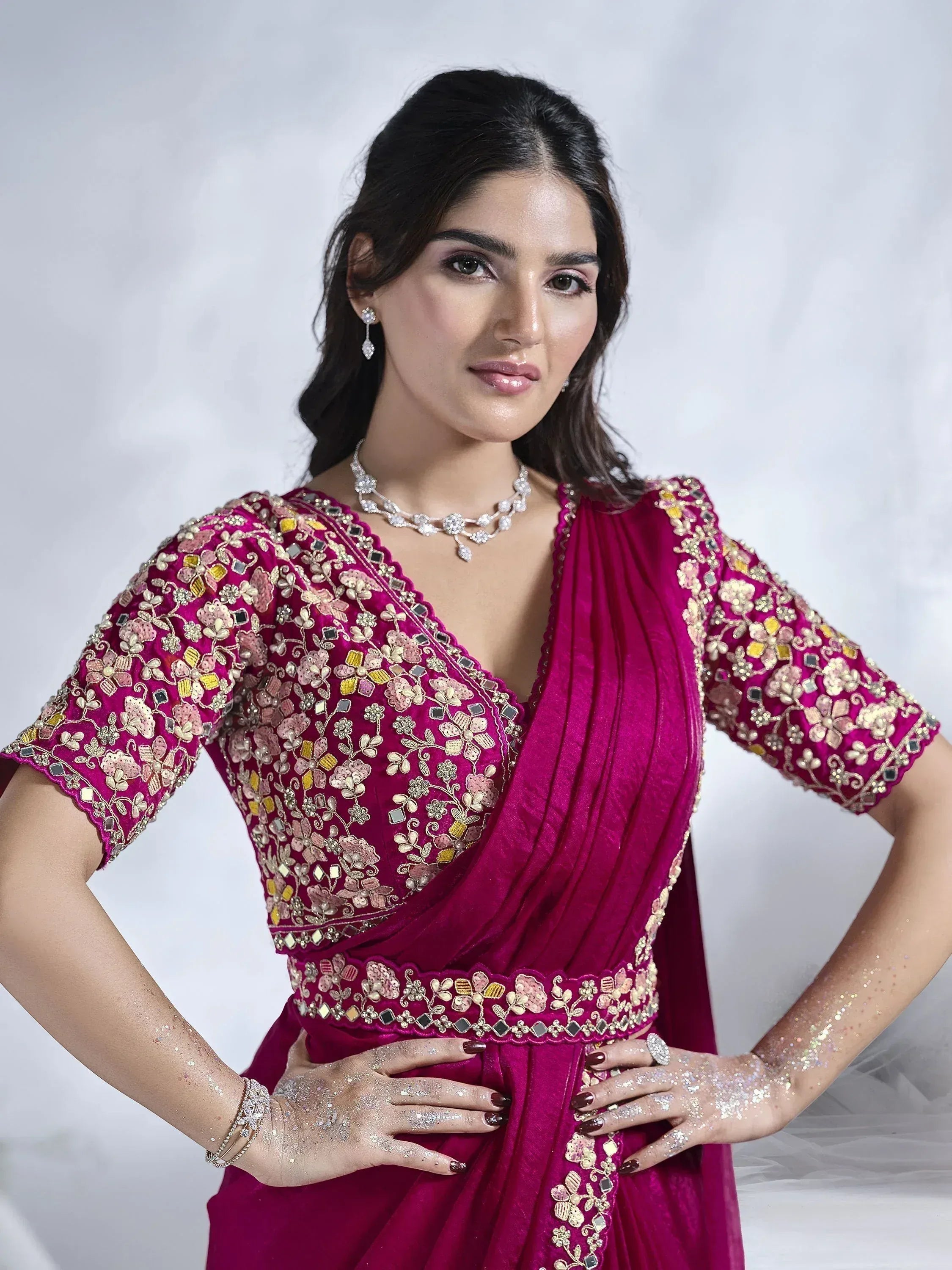 Woman in magenta embroidered ethnic gown with floral embellishments and jewelry, perfect for Indian occasions.