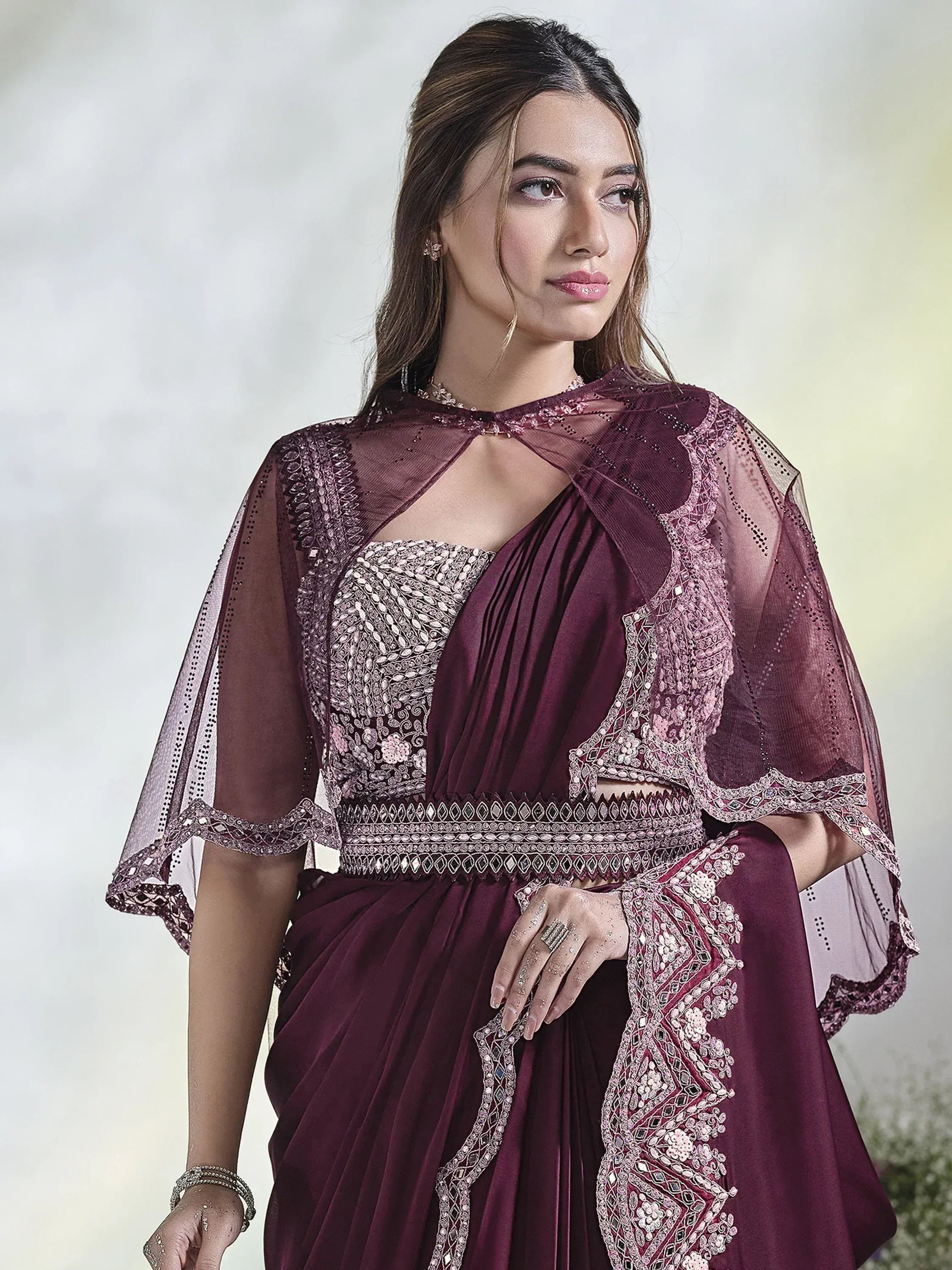 Elegant maroon ethnic gown with intricate embroidery and sheer cape, perfect for Indian celebrations.