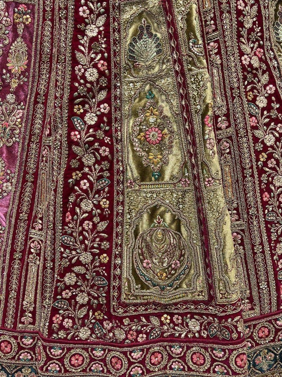 Luxury maroon velvet lehenga with gold floral embroidery and intricate zari work, perfect for Indian weddings.
