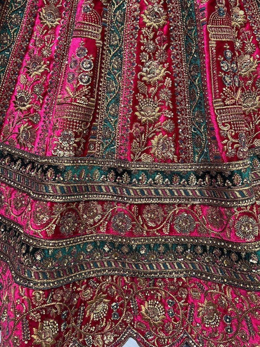 Richly embroidered pink and teal lehenga with gold floral motifs and intricate border detailing