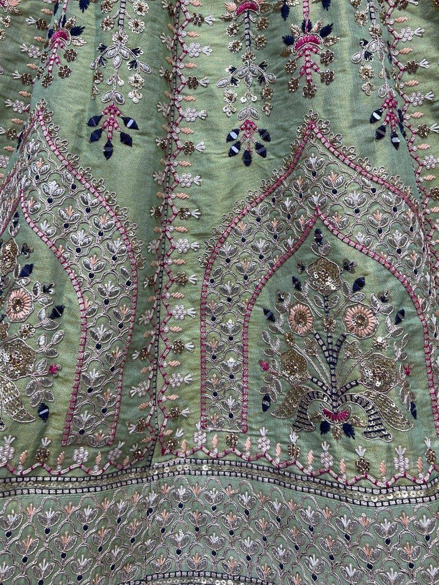 Green ethnic lehenga with intricate floral embroidery and mirror work, perfect for Indian weddings and festivals.