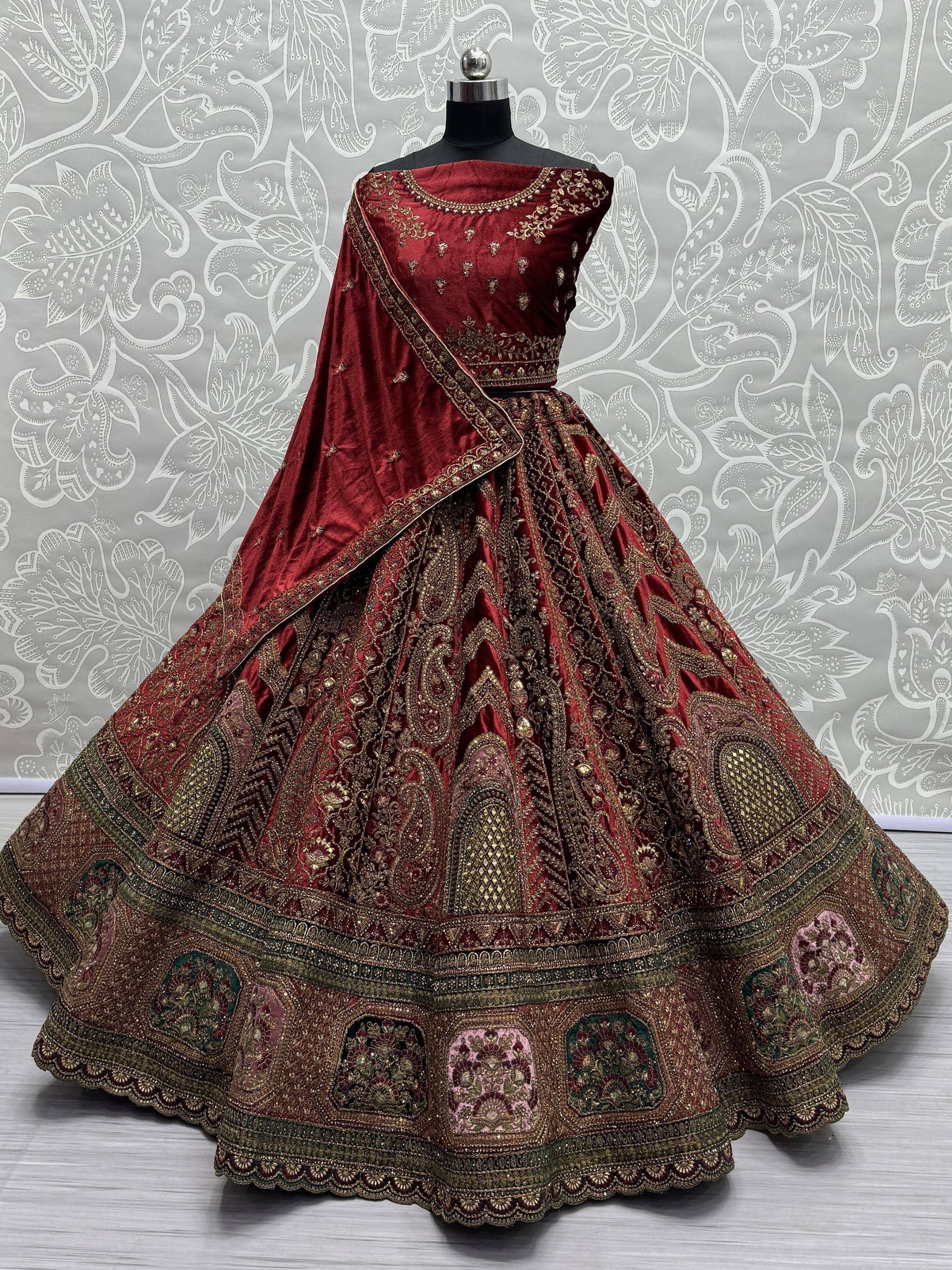 Luxury maroon velvet lehenga choli with heavy gold embroidery, perfect for Indian weddings and festive occasions.