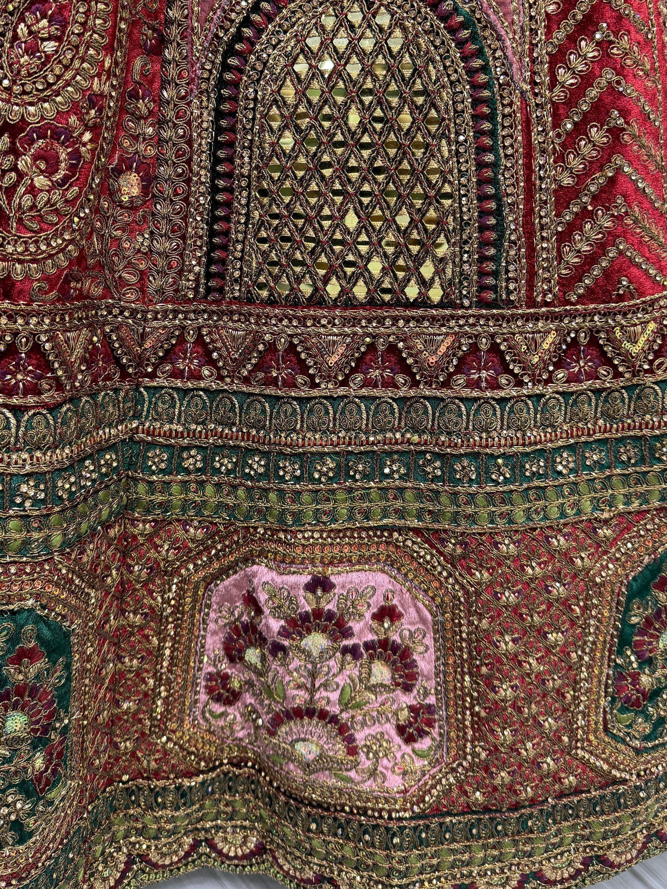 Richly embroidered Indian ethnic wear with gold thread, mirror work, and floral motifs in red and green