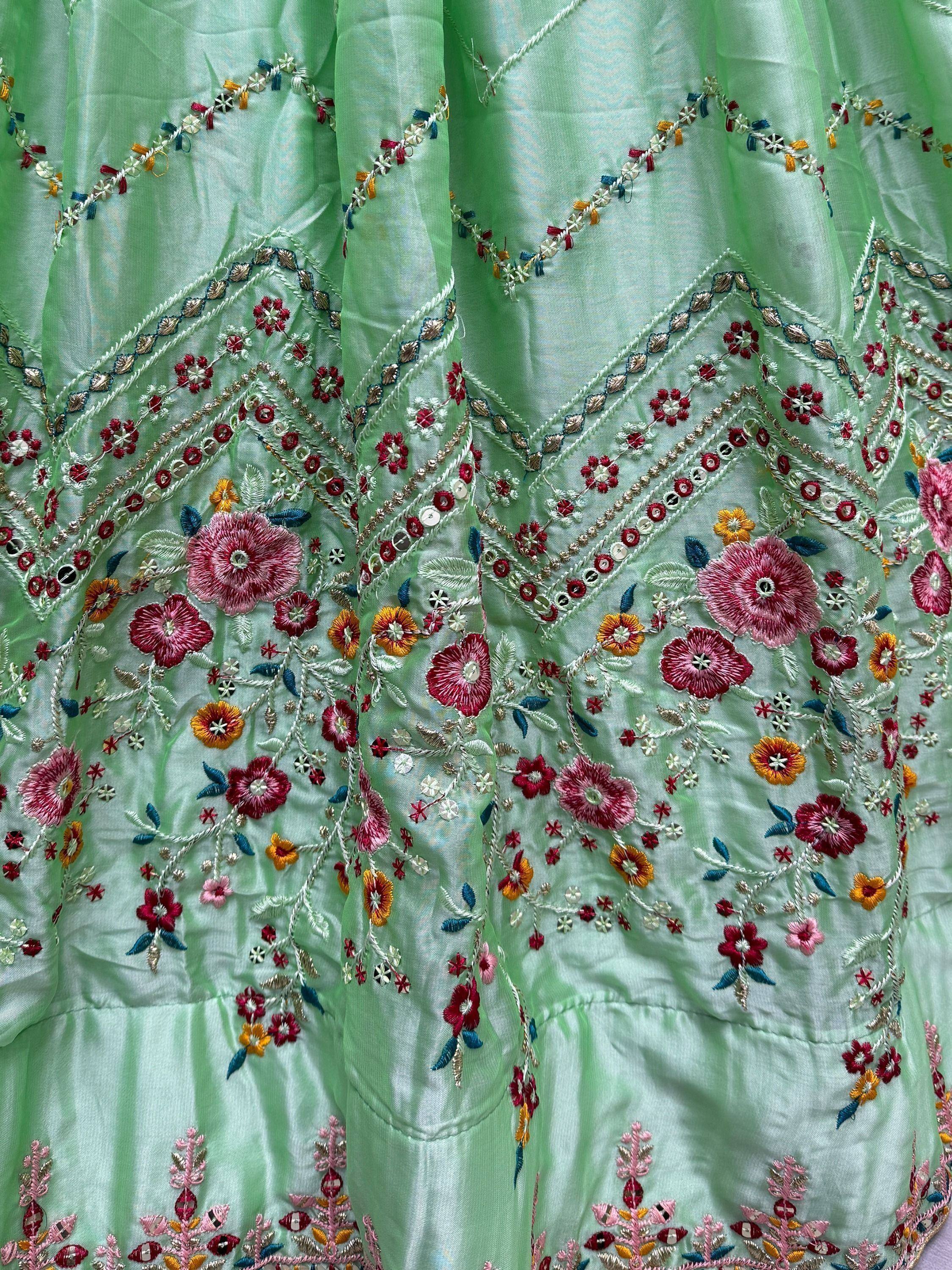 Mint green ethnic gown with vibrant floral embroidery and sequin detailing for festive occasions