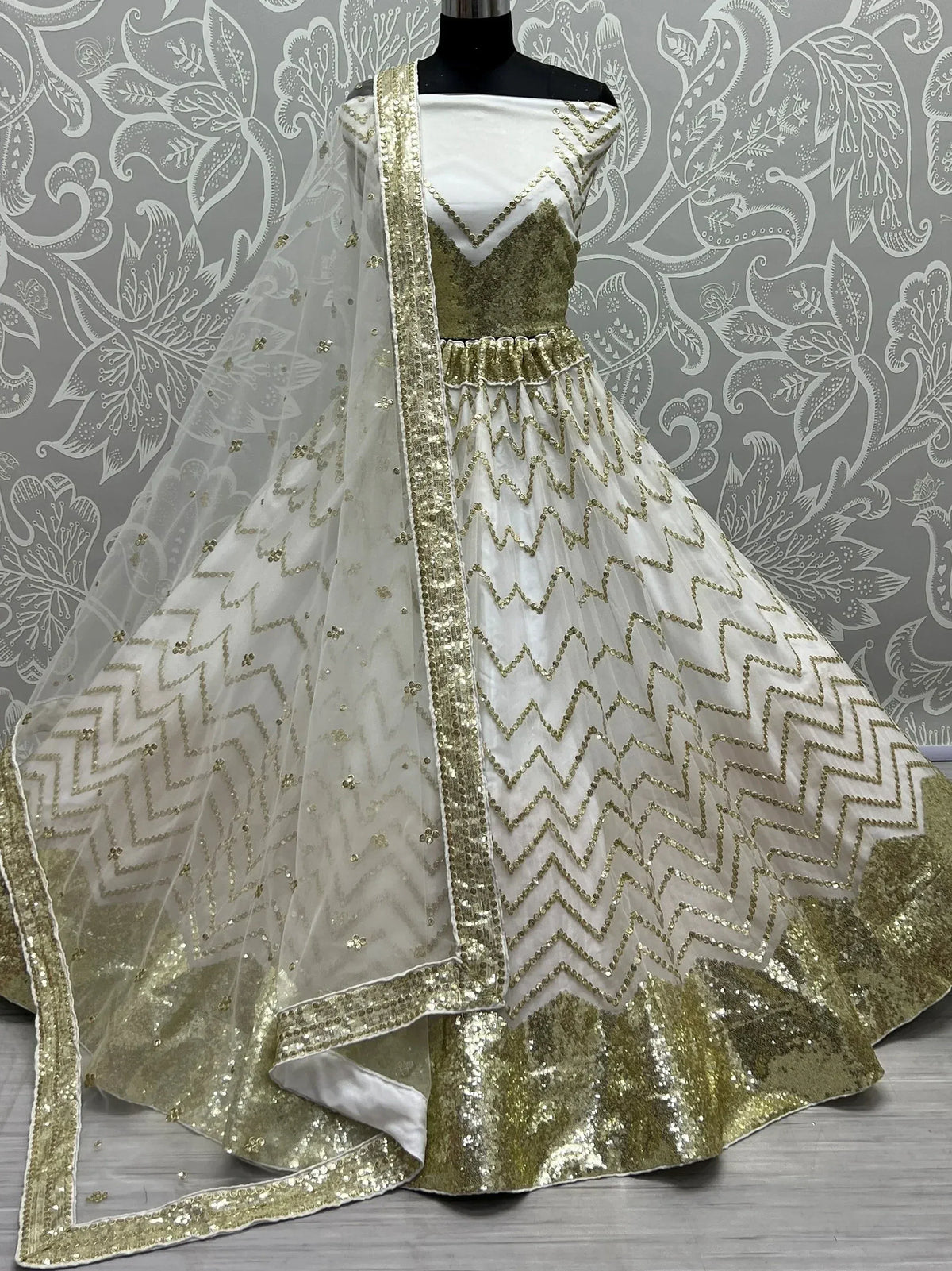 White and gold sequin lehenga choli with zigzag embroidery and matching dupatta, ideal for Indian ethnic occasions.