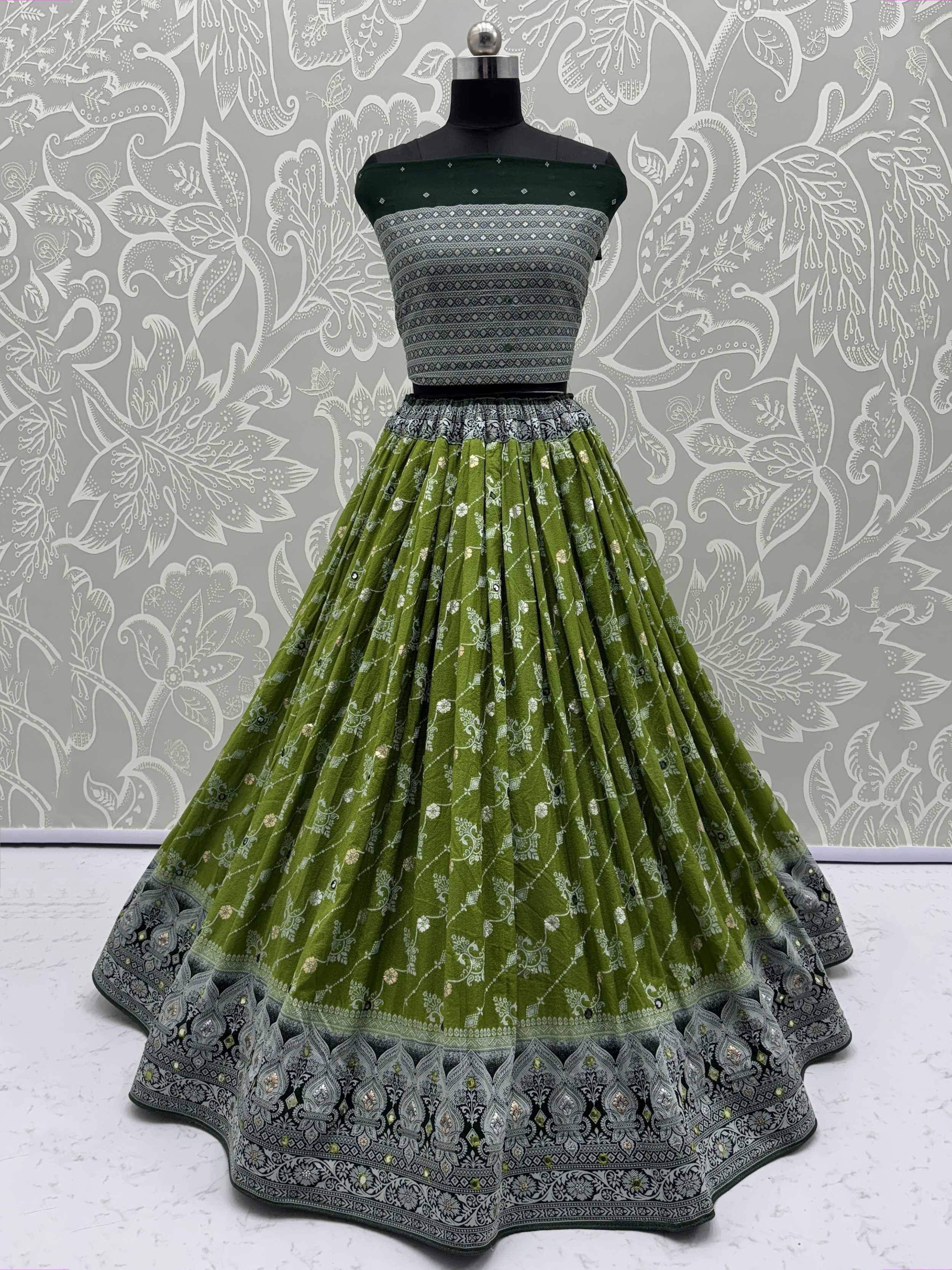 Green ethnic lehenga choli with silver embroidery and printed skirt, displayed on mannequin