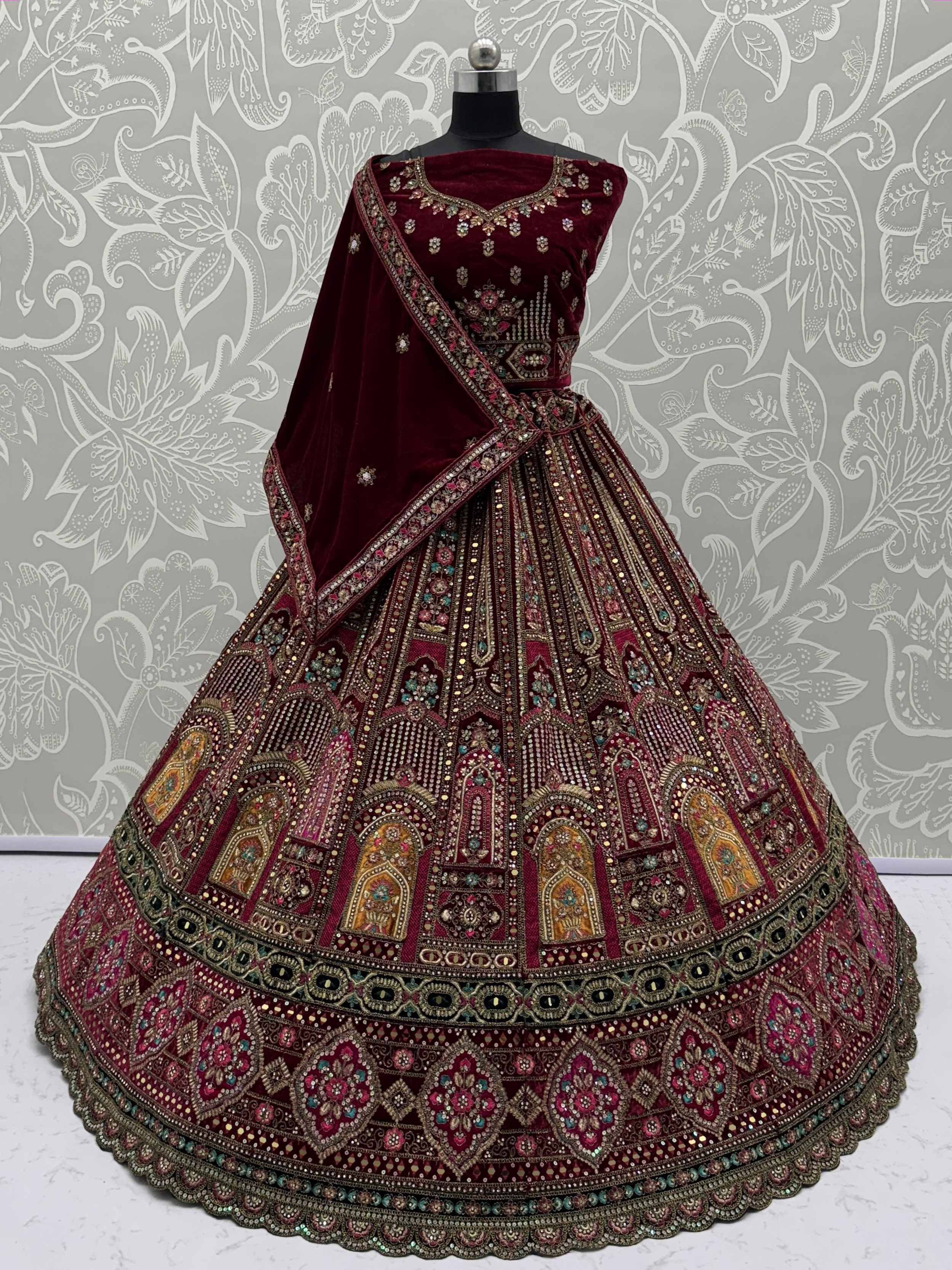 Maroon velvet designer lehenga choli with heavy embroidery and mirror work, perfect for Indian weddings