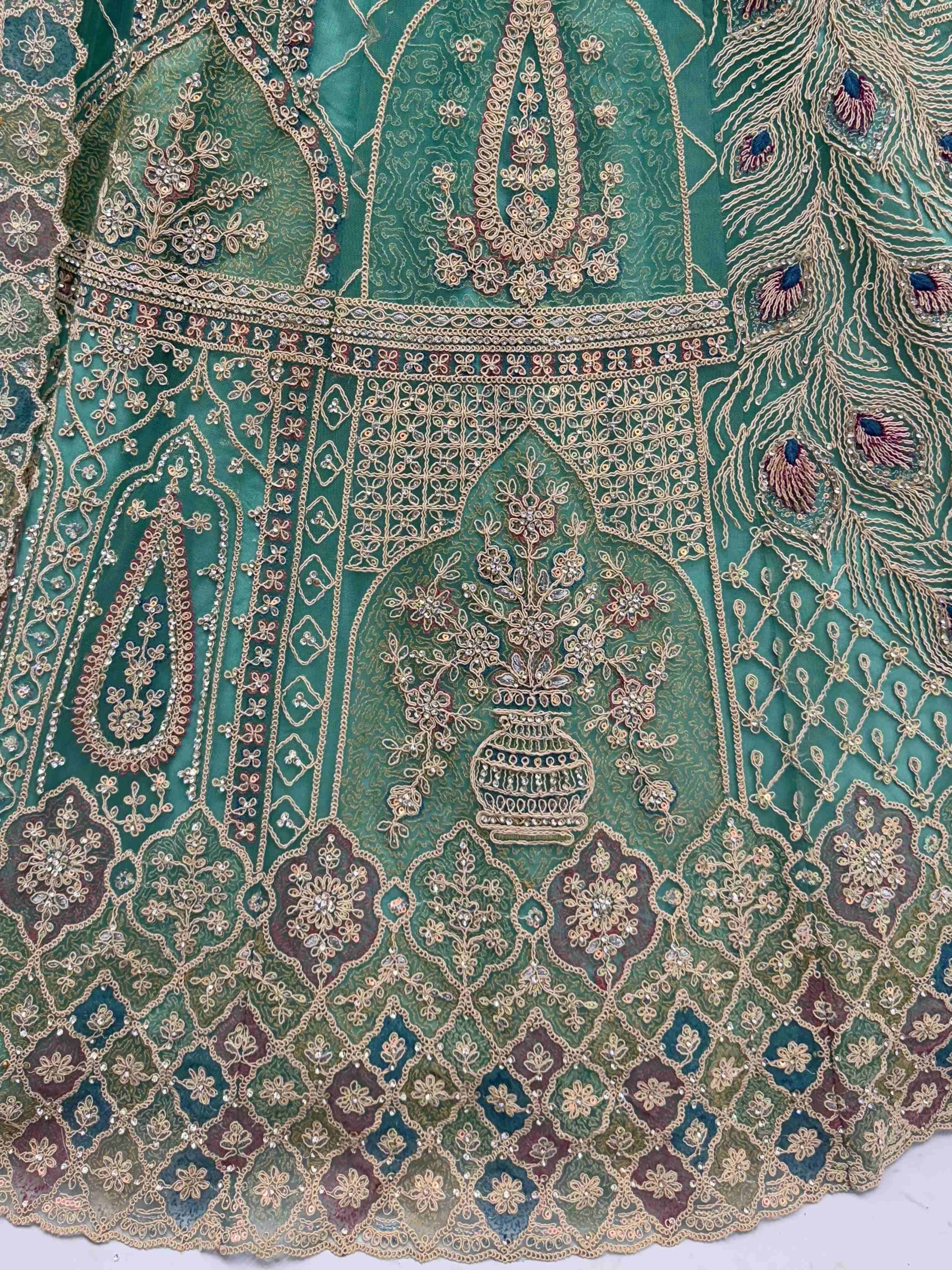 Emerald green designer lehenga with intricate gold embroidery, floral motifs, and peacock feather details.
