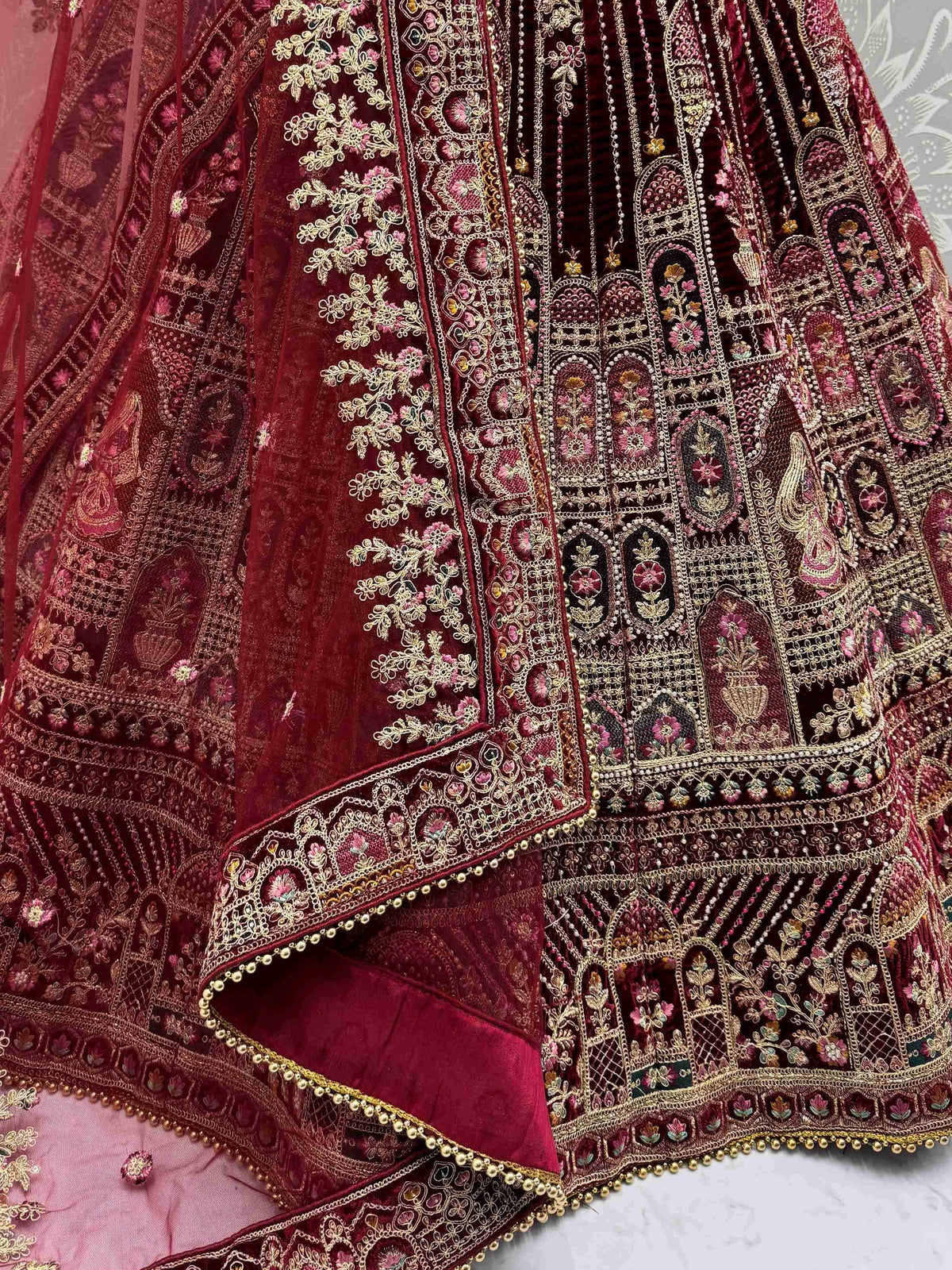 Luxury maroon lehenga choli with intricate gold embroidery and floral motifs, perfect for Indian weddings.