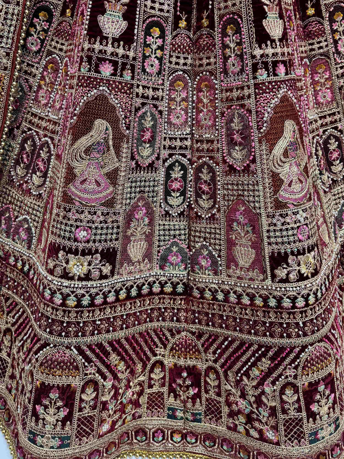 Luxury maroon ethnic gown with intricate floral embroidery, zari work, and pearl detailing for weddings