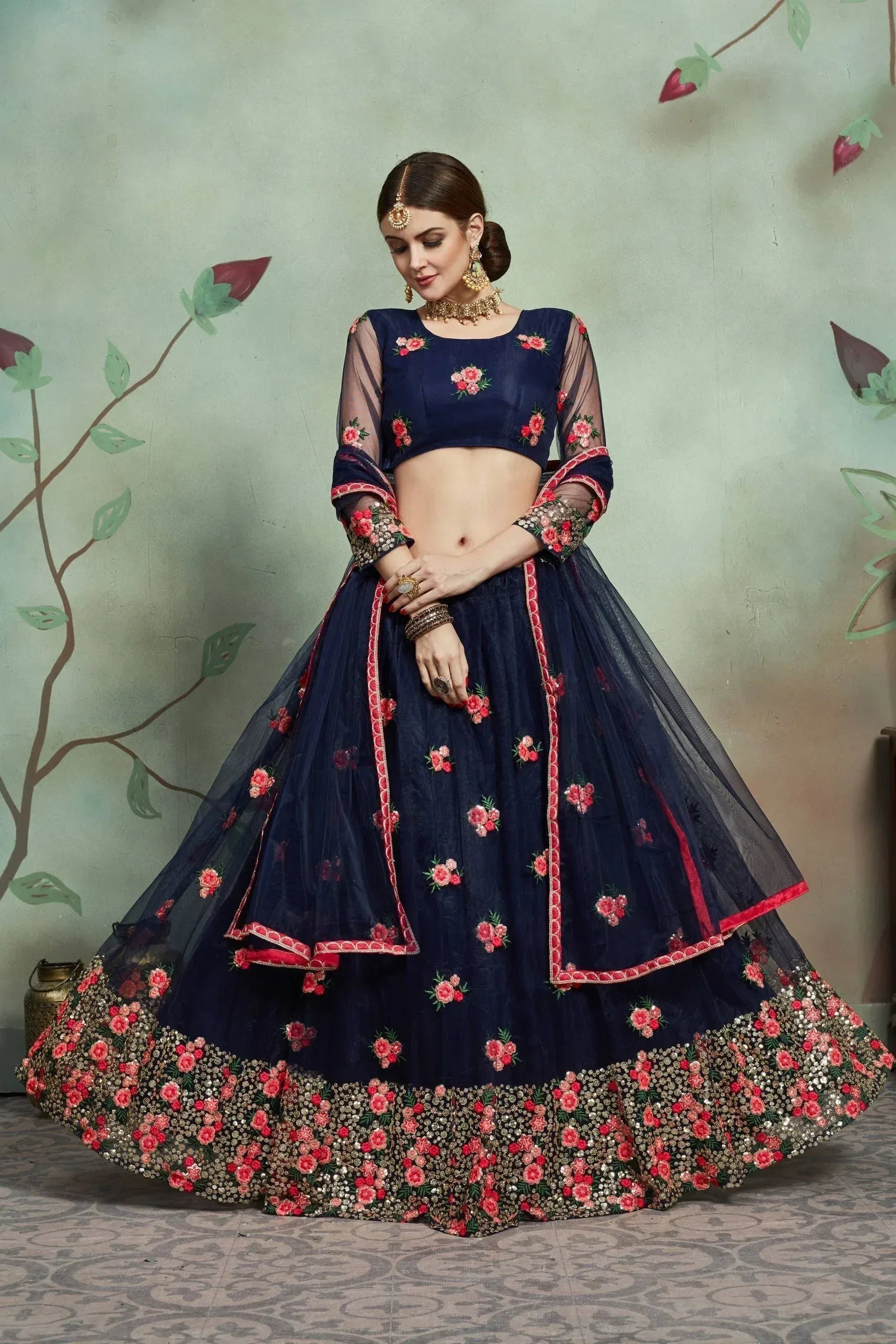 Navy blue designer lehenga choli with pink floral embroidery and sheer sleeves, perfect for Indian weddings and festivals.