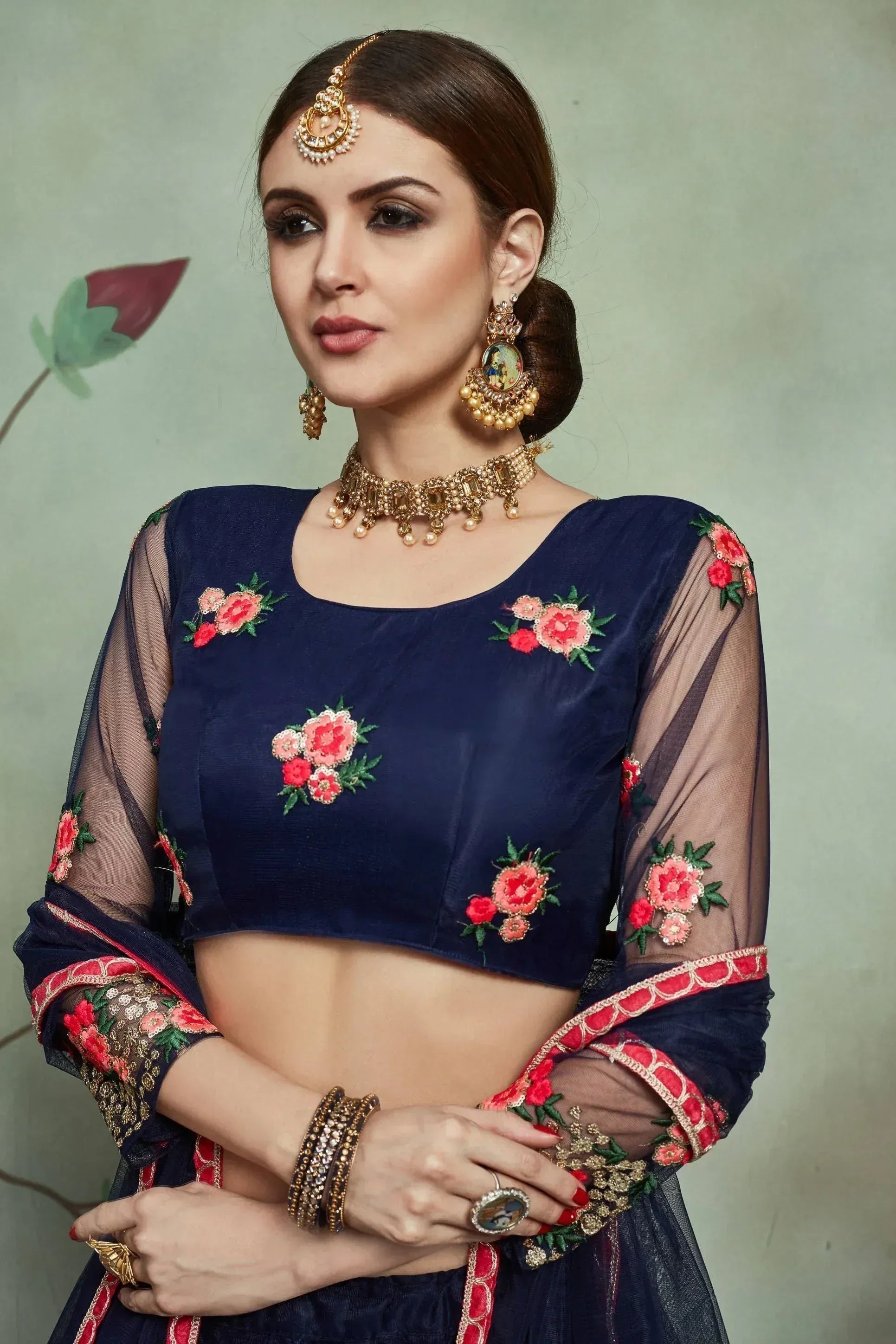 Navy blue embroidered lehenga choli with floral motifs, sheer sleeves, and traditional Indian jewelry