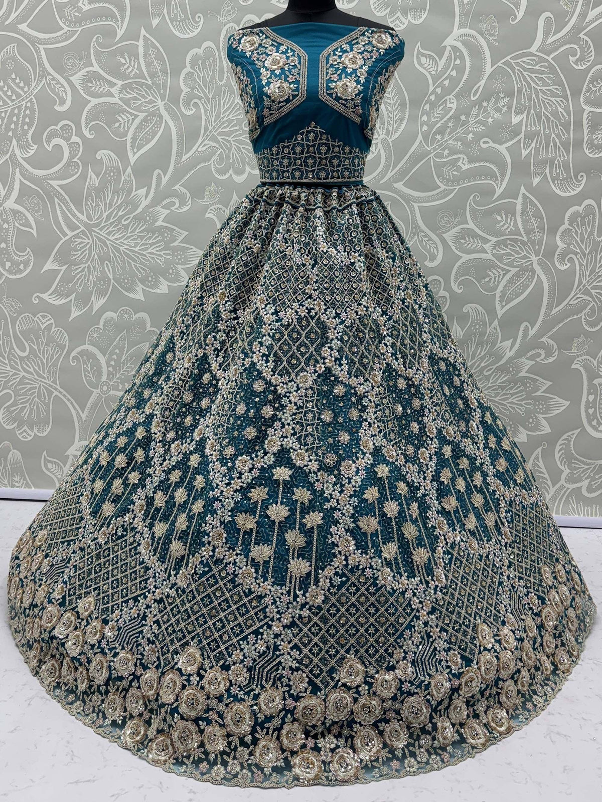 Teal designer lehenga choli with heavy gold embroidery and floral motifs, perfect for Indian weddings and festive occasions.