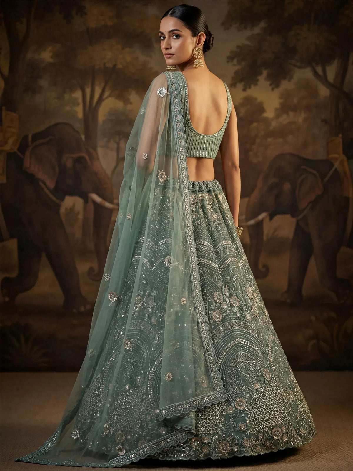 Elegant sage green designer lehenga choli with intricate embroidery and sheer dupatta, perfect for weddings.