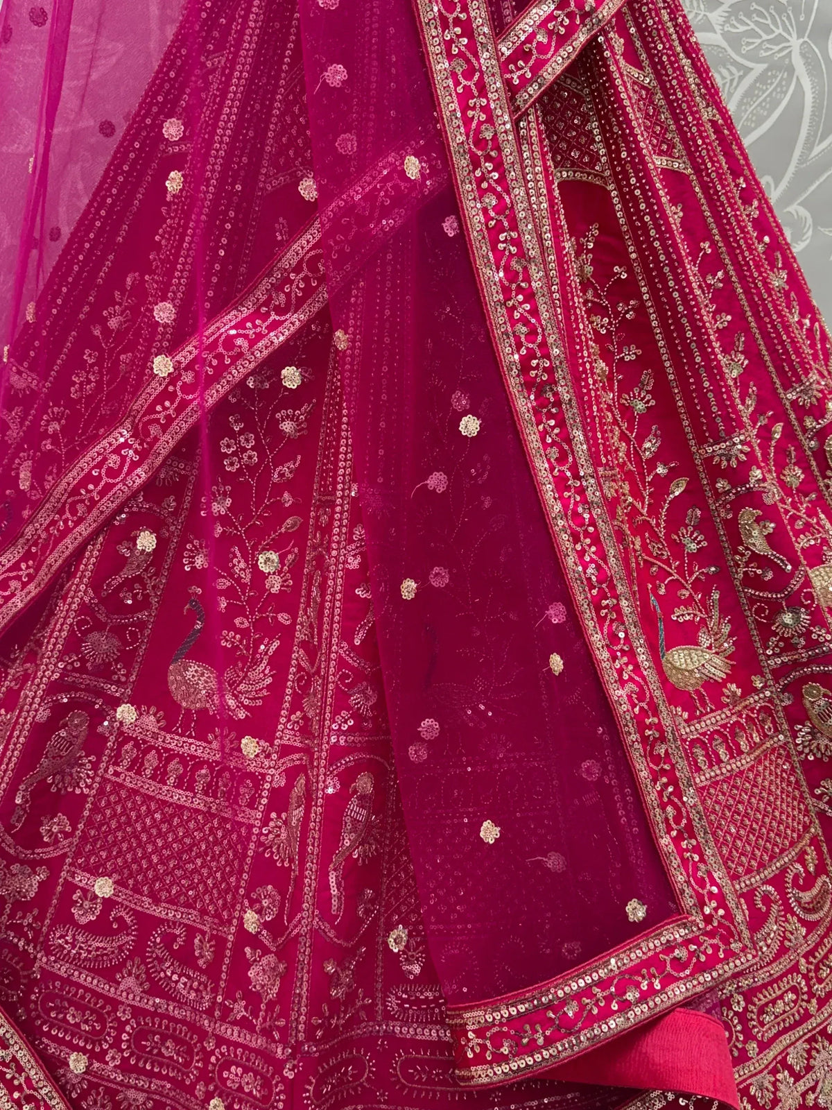 Close-up of a magenta pink designer lehenga with intricate gold zari embroidery and sequins