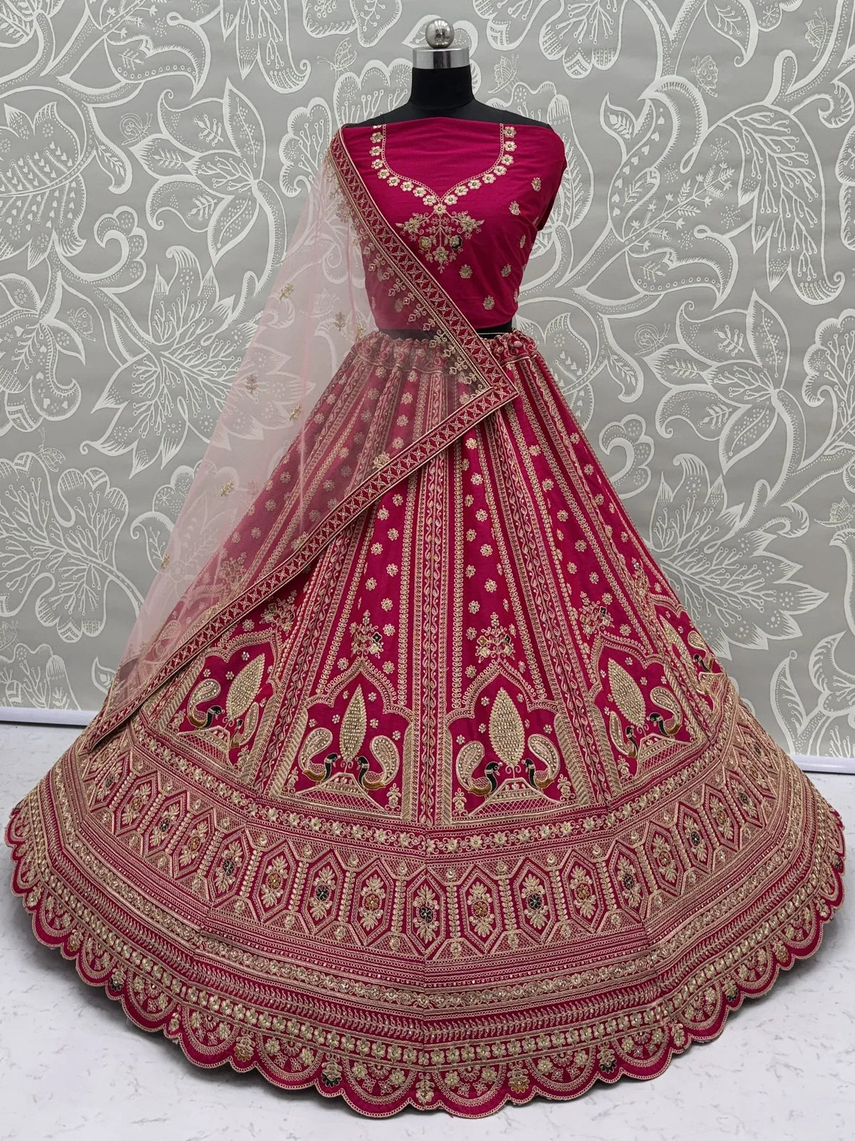 Intricately embroidered magenta designer lehenga choli with a sheer dupatta on a mannequin