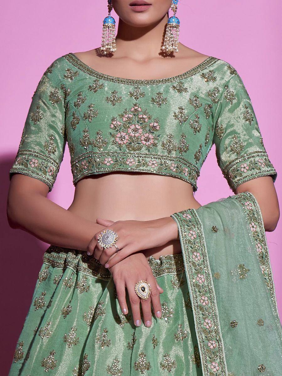 Mint green embroidered lehenga choli with floral motifs and gold detailing, paired with statement jewelry.
